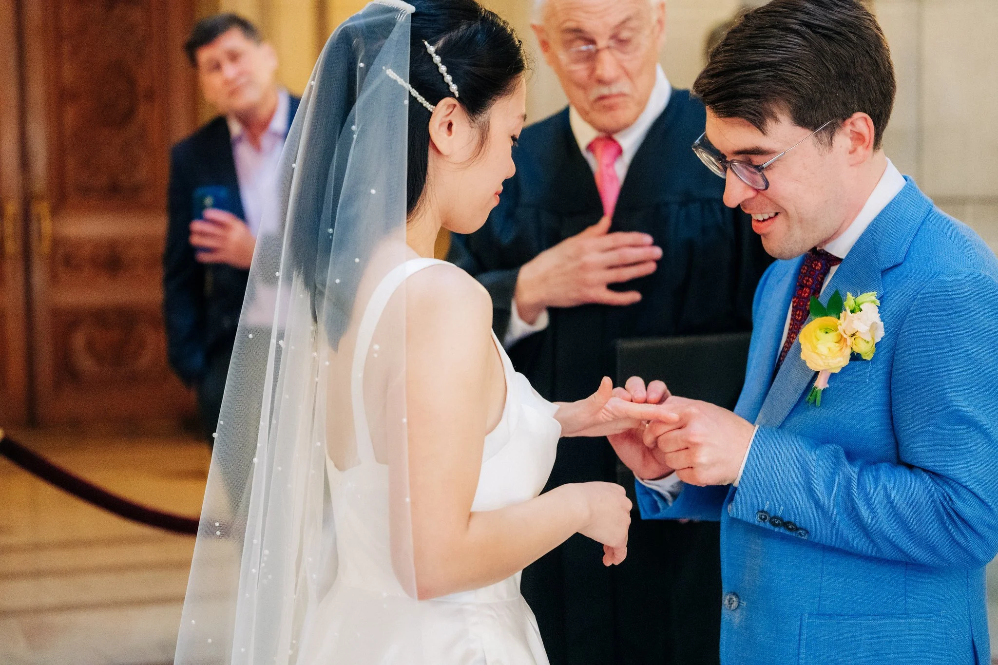 Groom putting ring on bride during San Francisco City Hall wedding ceremony