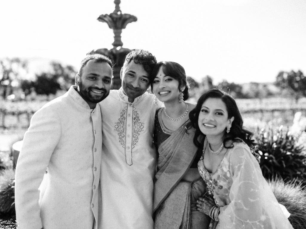 Bride and groom posing with their siblings in front of a fountain