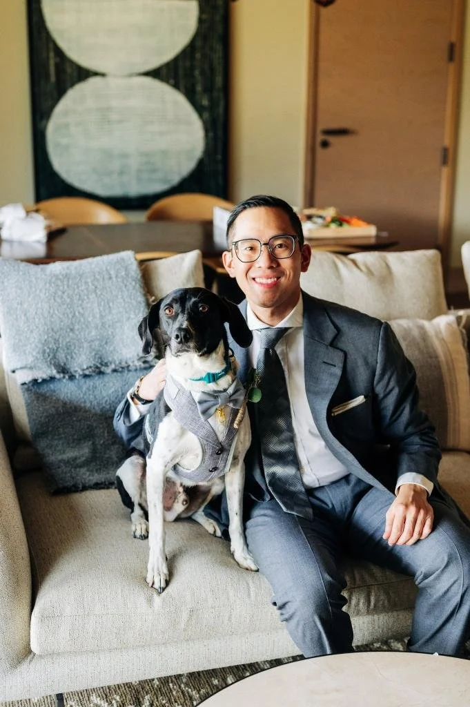 Groom sitting with his dog on a couch before the wedding ceremony