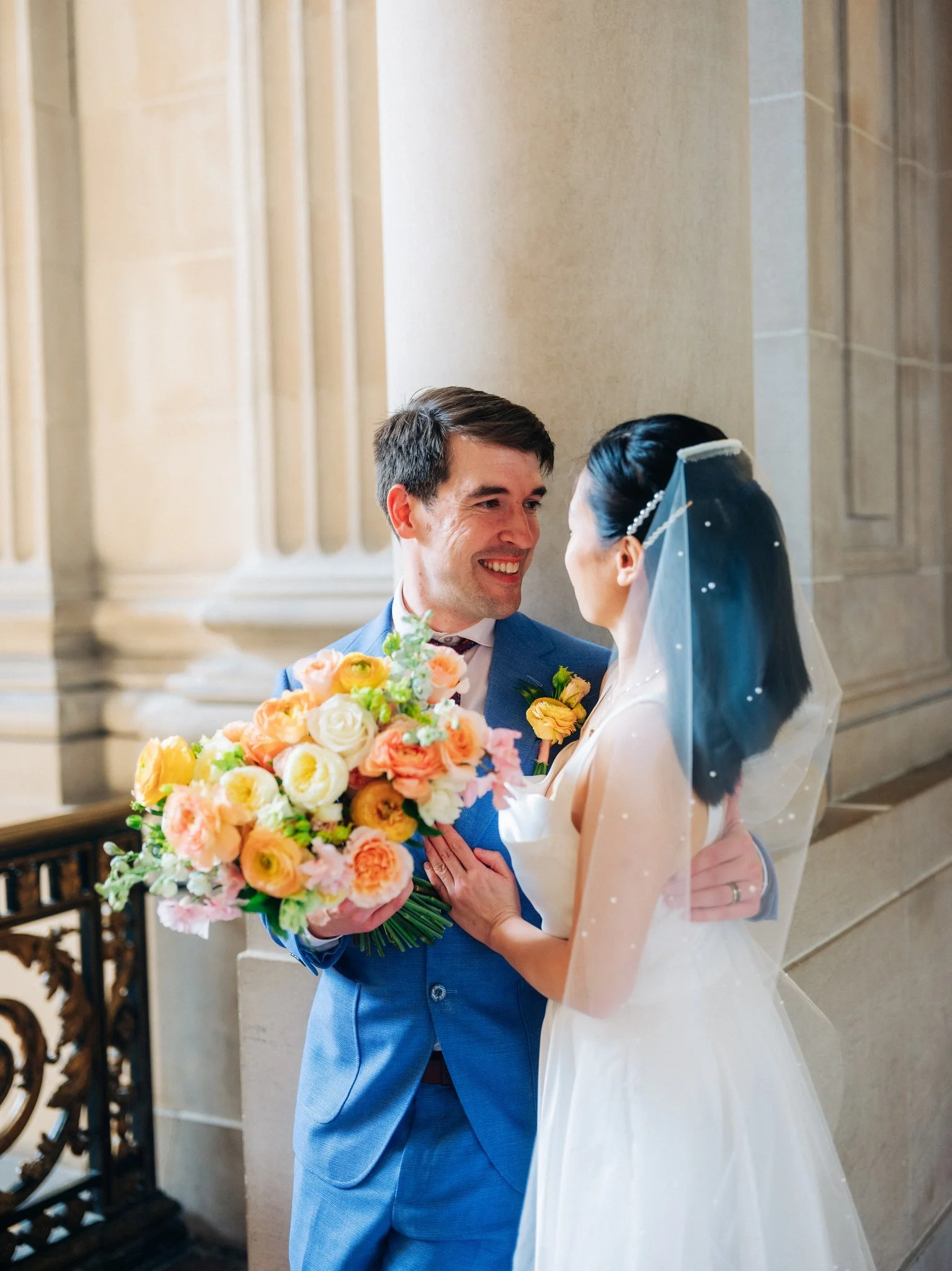Bride holding flowers looking into groom’s eyes during San Francisco City Hall wedding