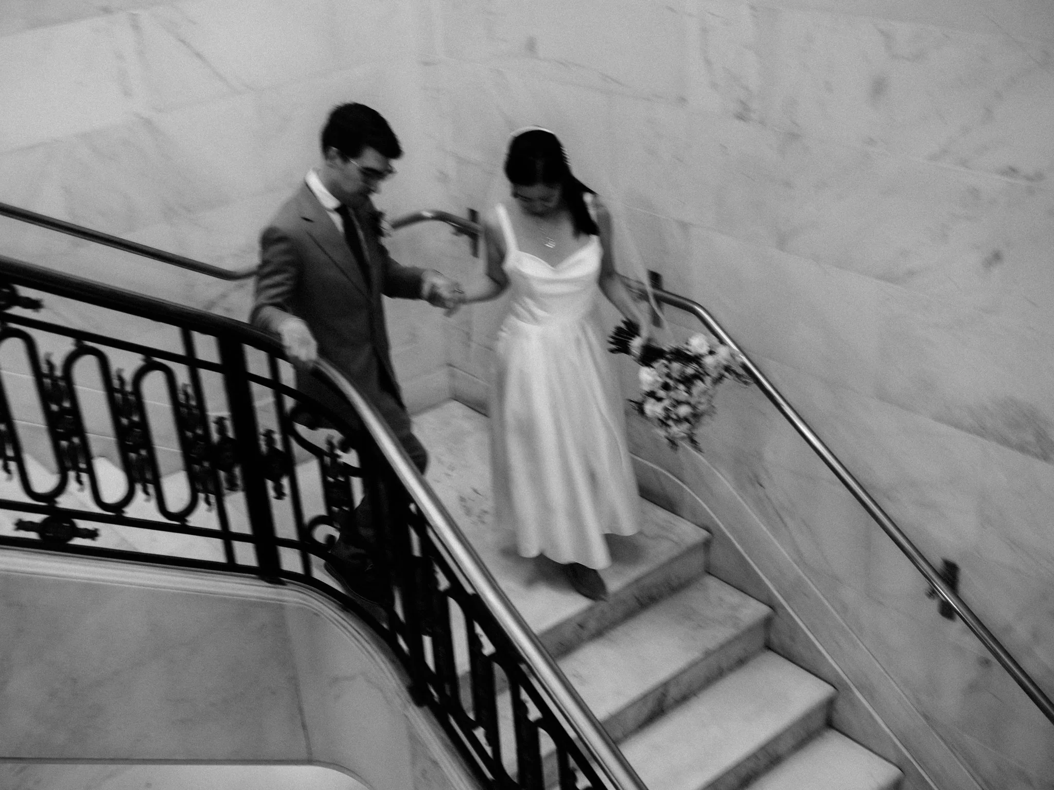 Bride and groom holding hands walking down staircase at San Francisco City Hall wedding