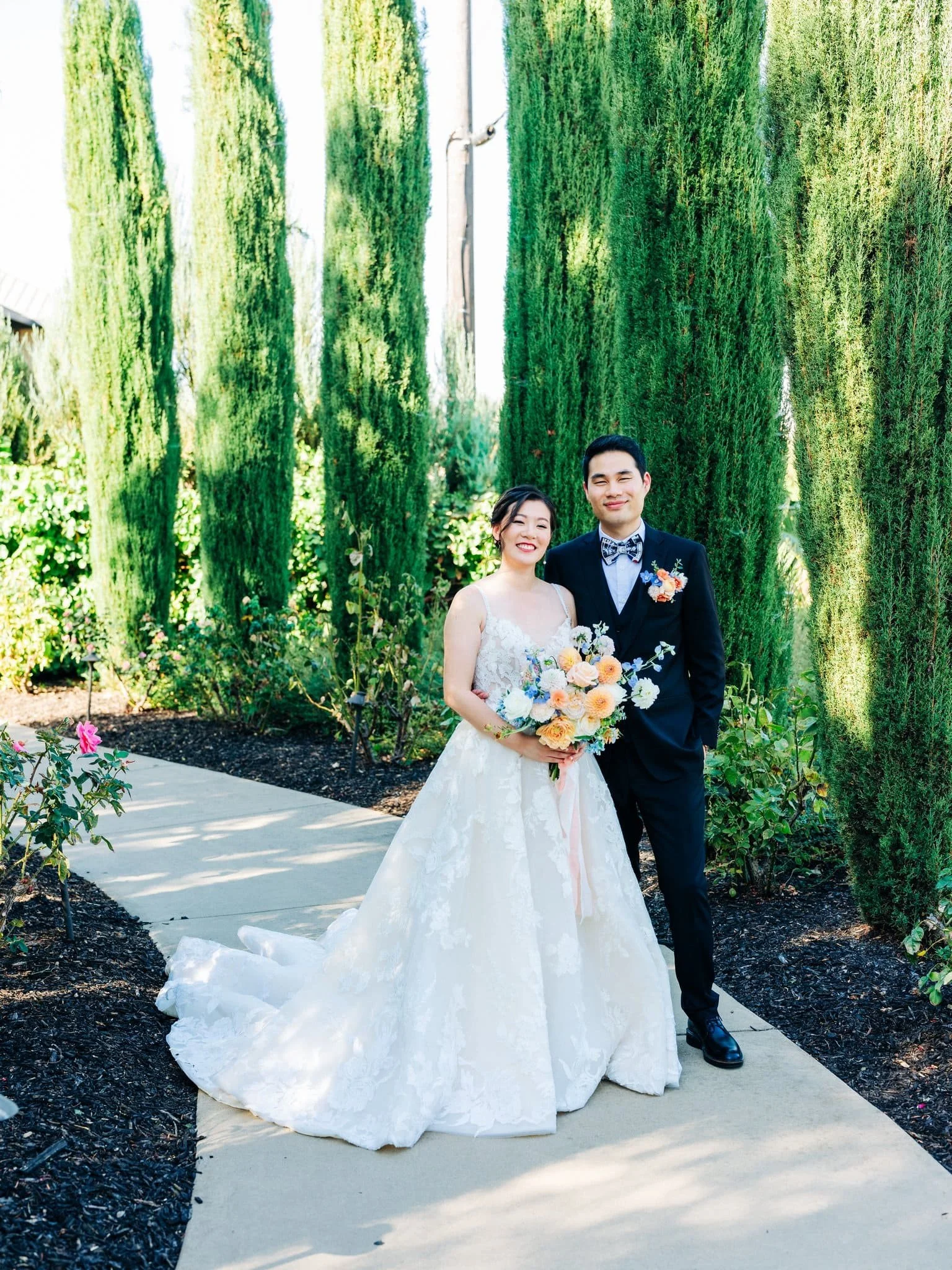 bride and groom posing with flowers on path couples portraits palm event center pleasanton wedding