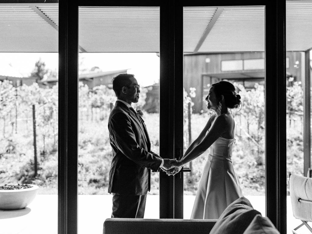 Bride and groom holding hands and smiling at each other before the ceremony