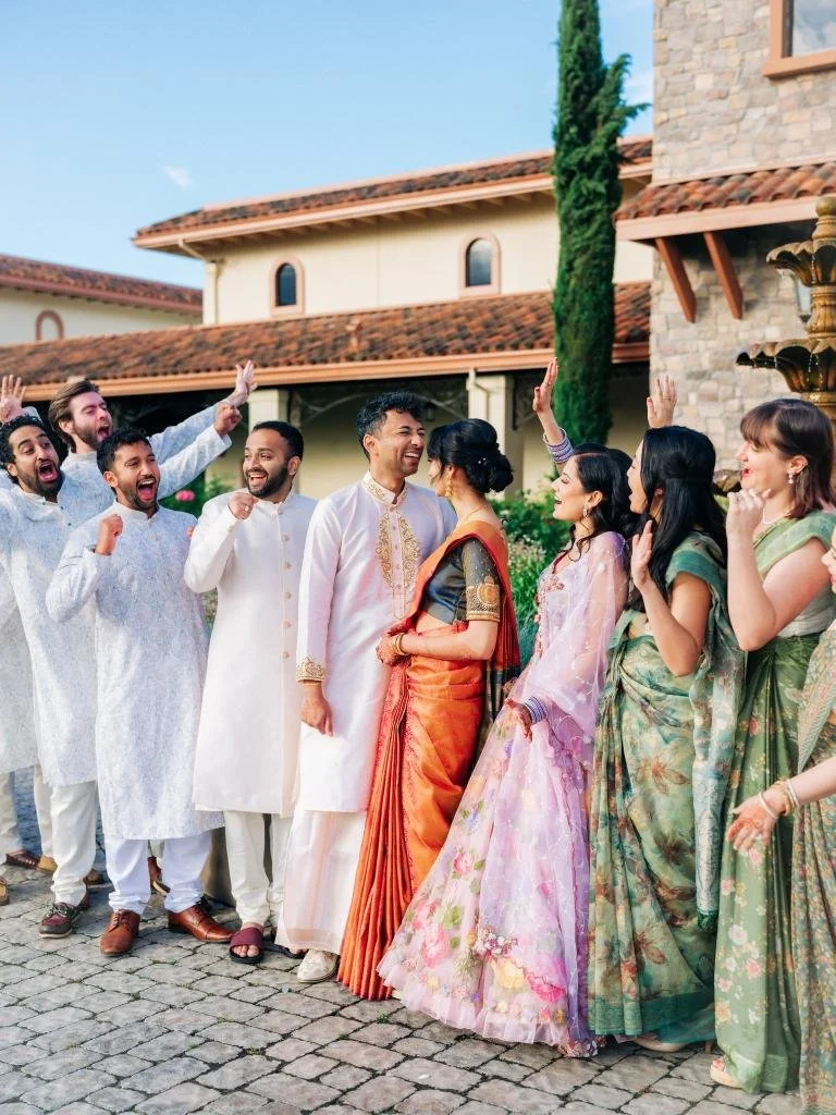 Bride and groom embracing while their wedding party celebrates around them