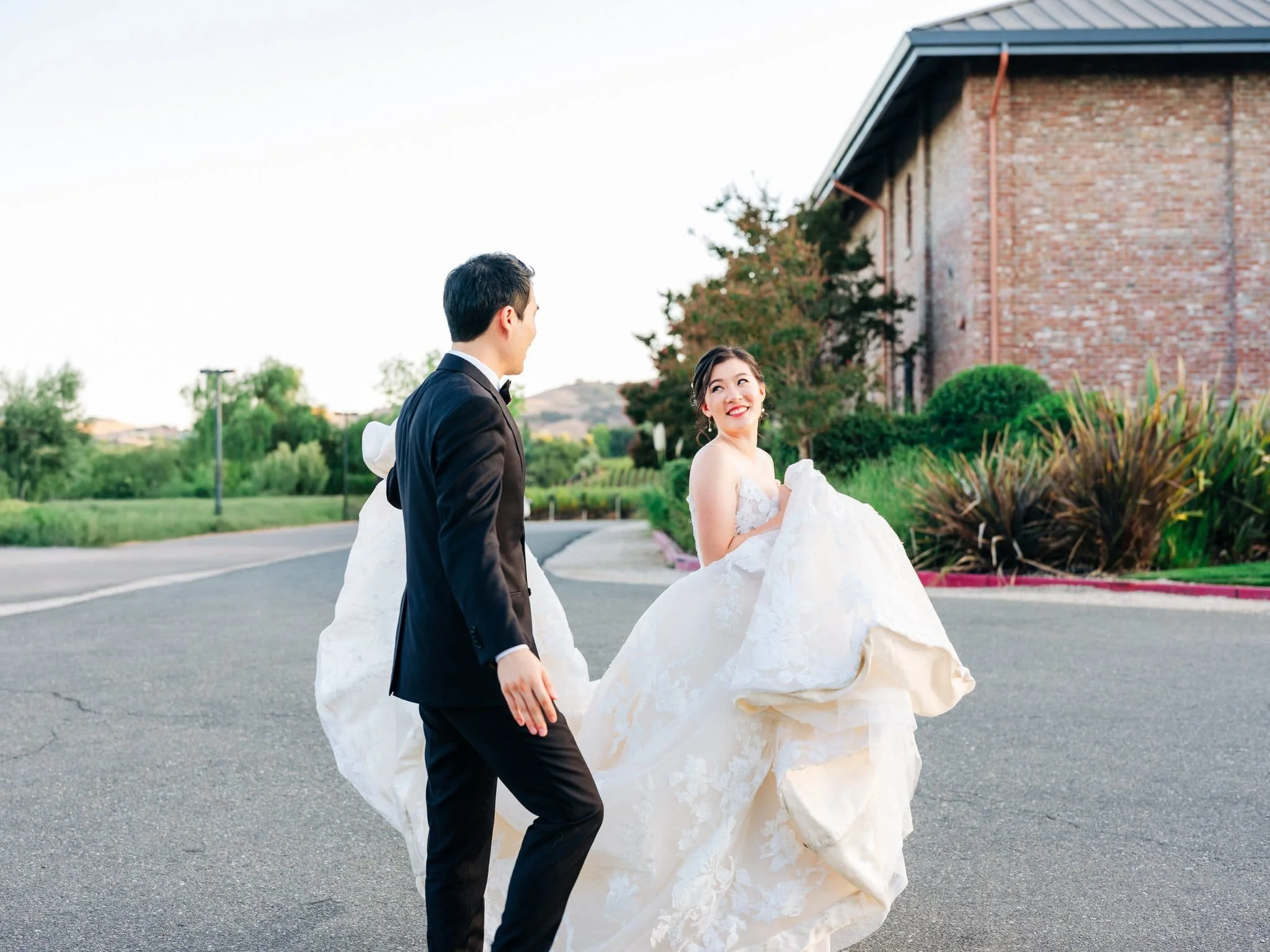 groom holding bride dress as she looks back at him couples portrait palm event center pleasanton wedding