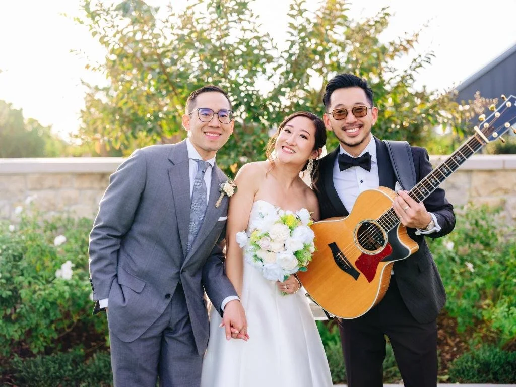 Bride and groom standing beside their wedding guitarist