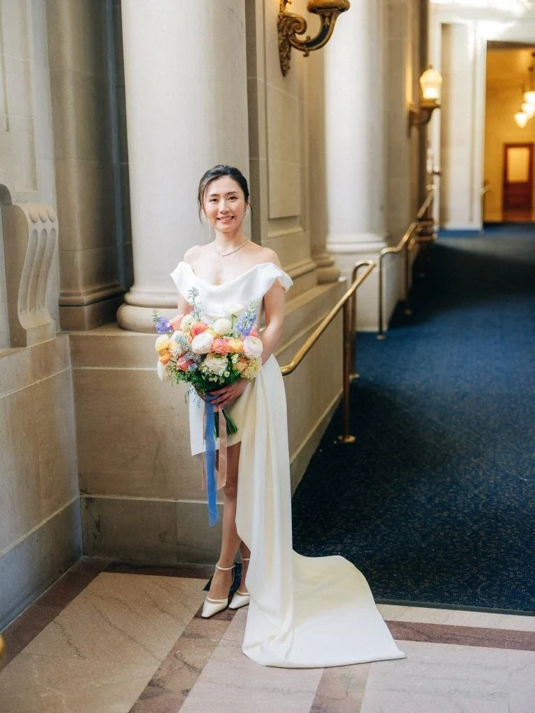 Bride standing in a hallway at San Francisco City Hall holding her wedding bouquet.