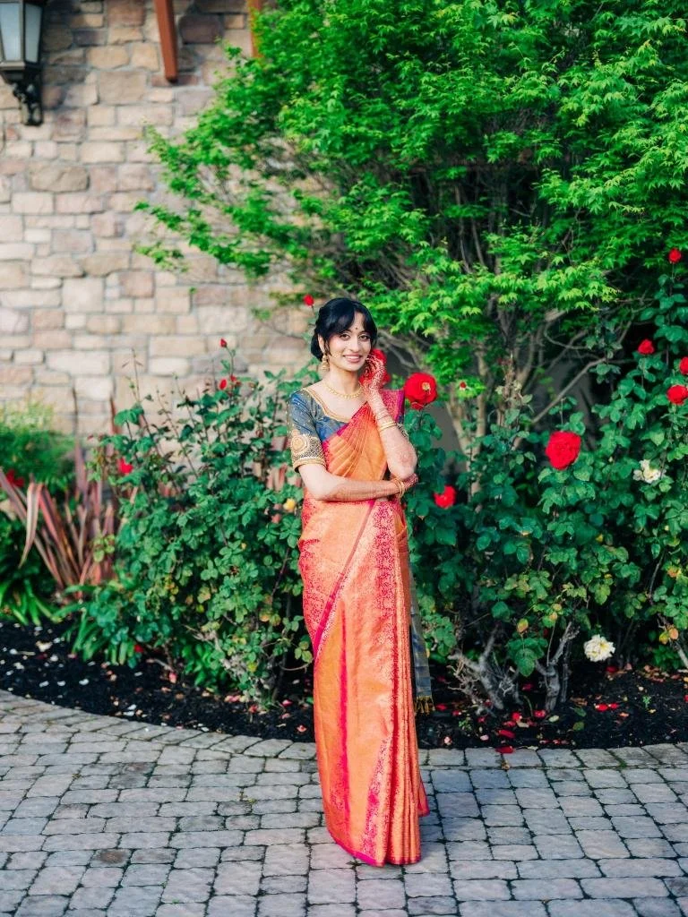 Bride posing for a portrait in front of a wall of roses