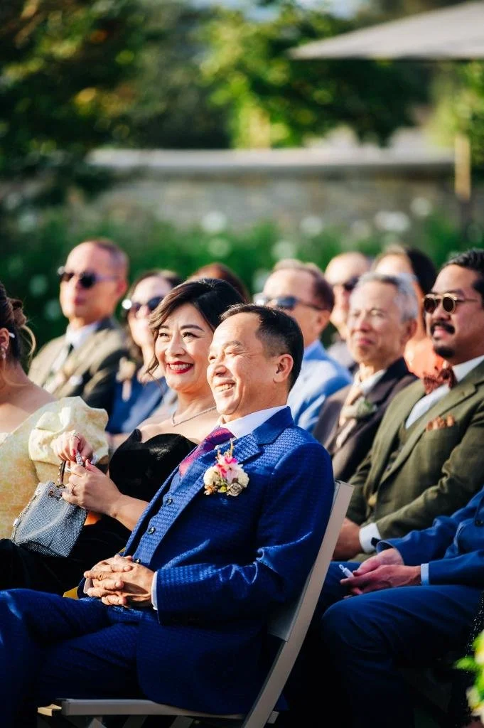 Wedding guests smiling as they watch the ceremony