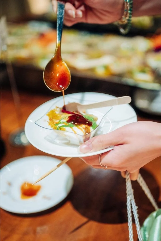 Close-up of food being plated with dressing added during the wedding reception