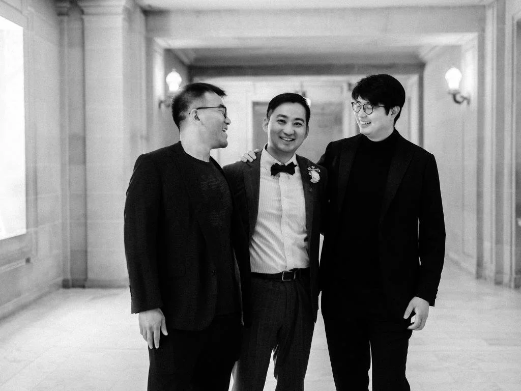 Groom smiling with two friends during the couple's San Francisco City Hall elopement.
