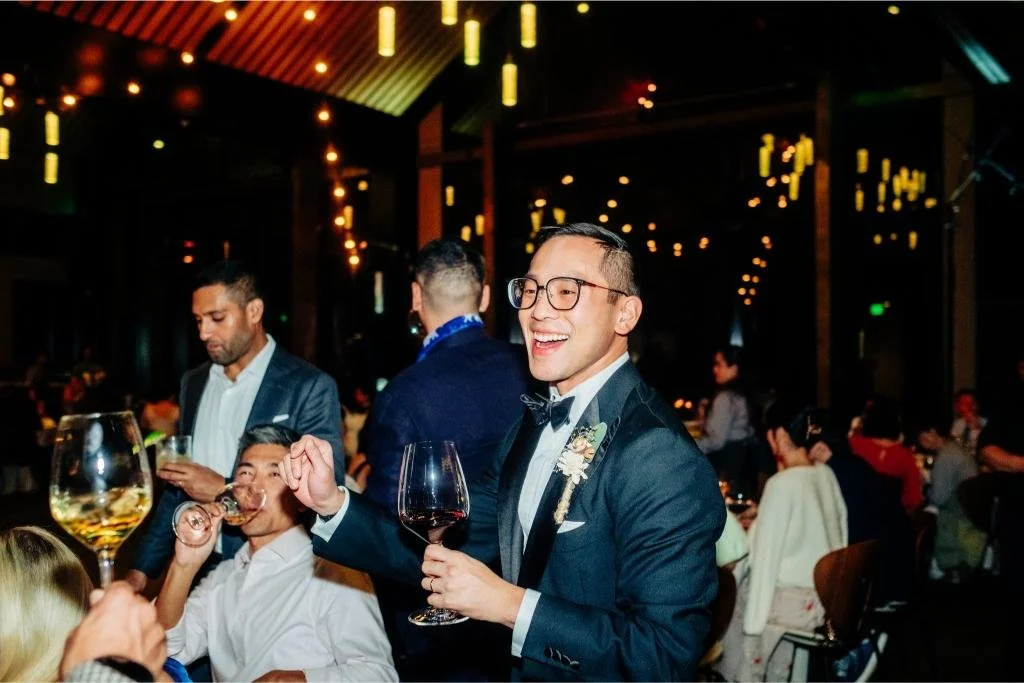 Groom walking through the reception with a wine glass while greeting guests