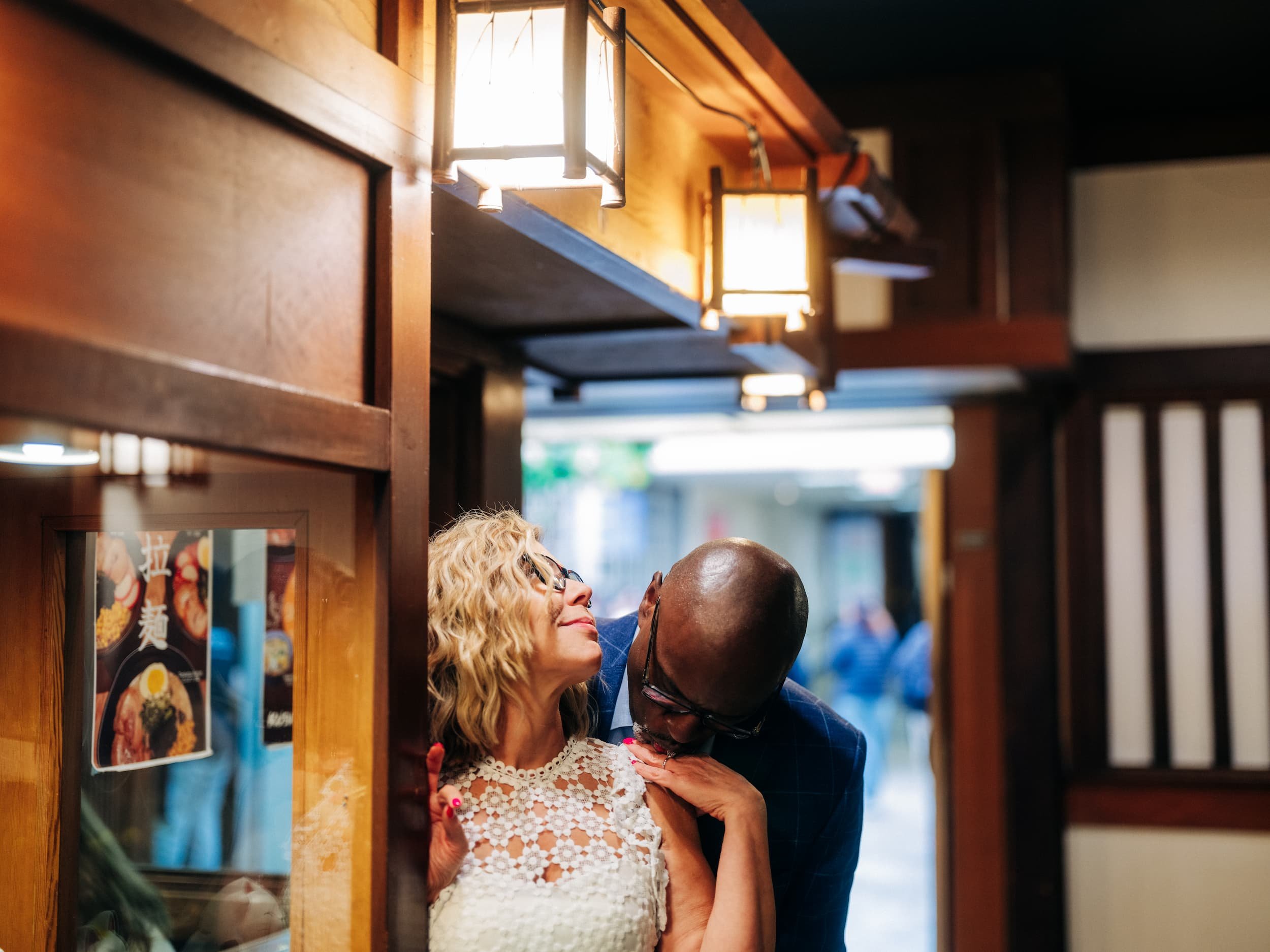 Man kissing woman’s hand during romantic engagement session at restaurant