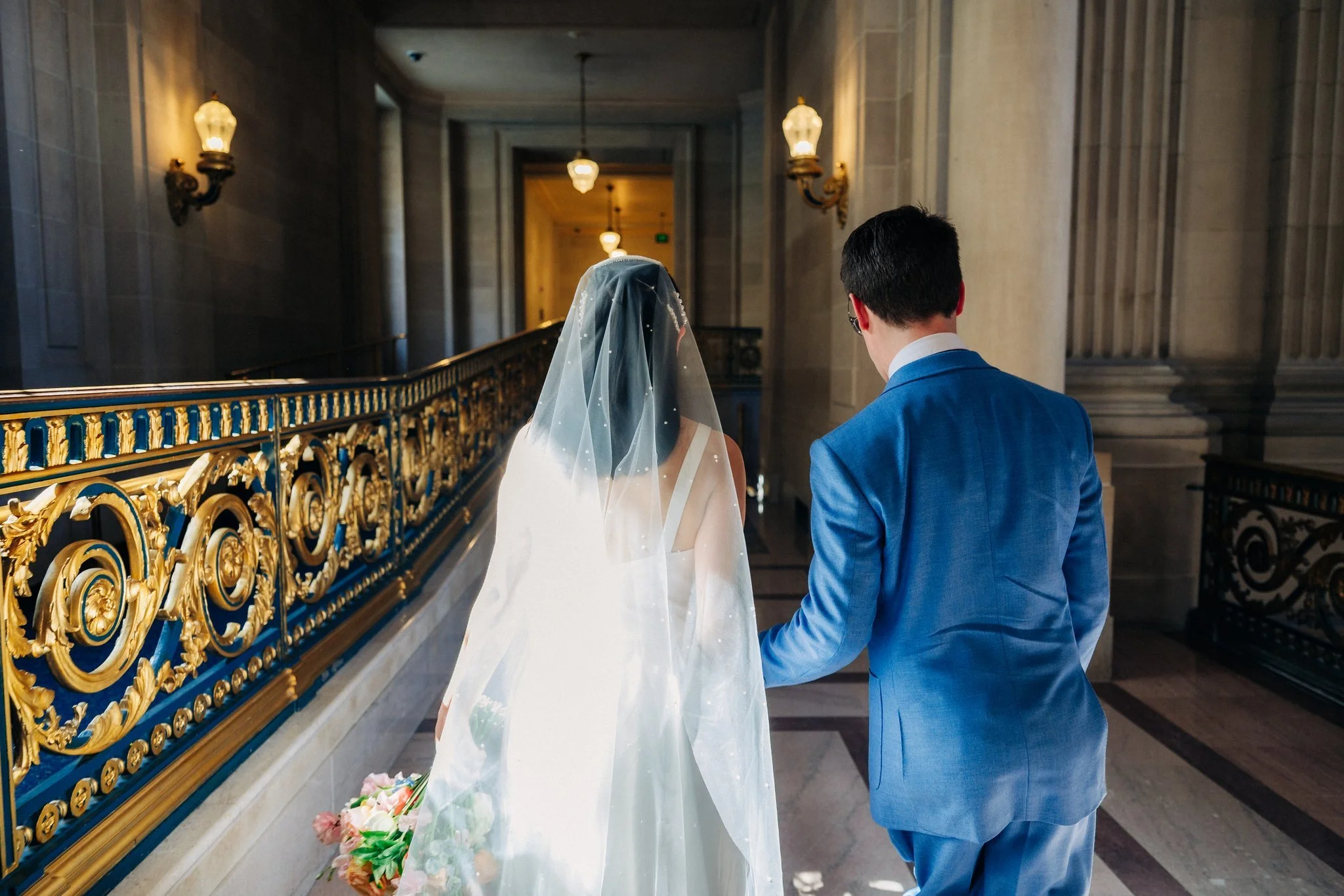 Bride and groom walking down hallway from behind at San Francisco City Hall wedding