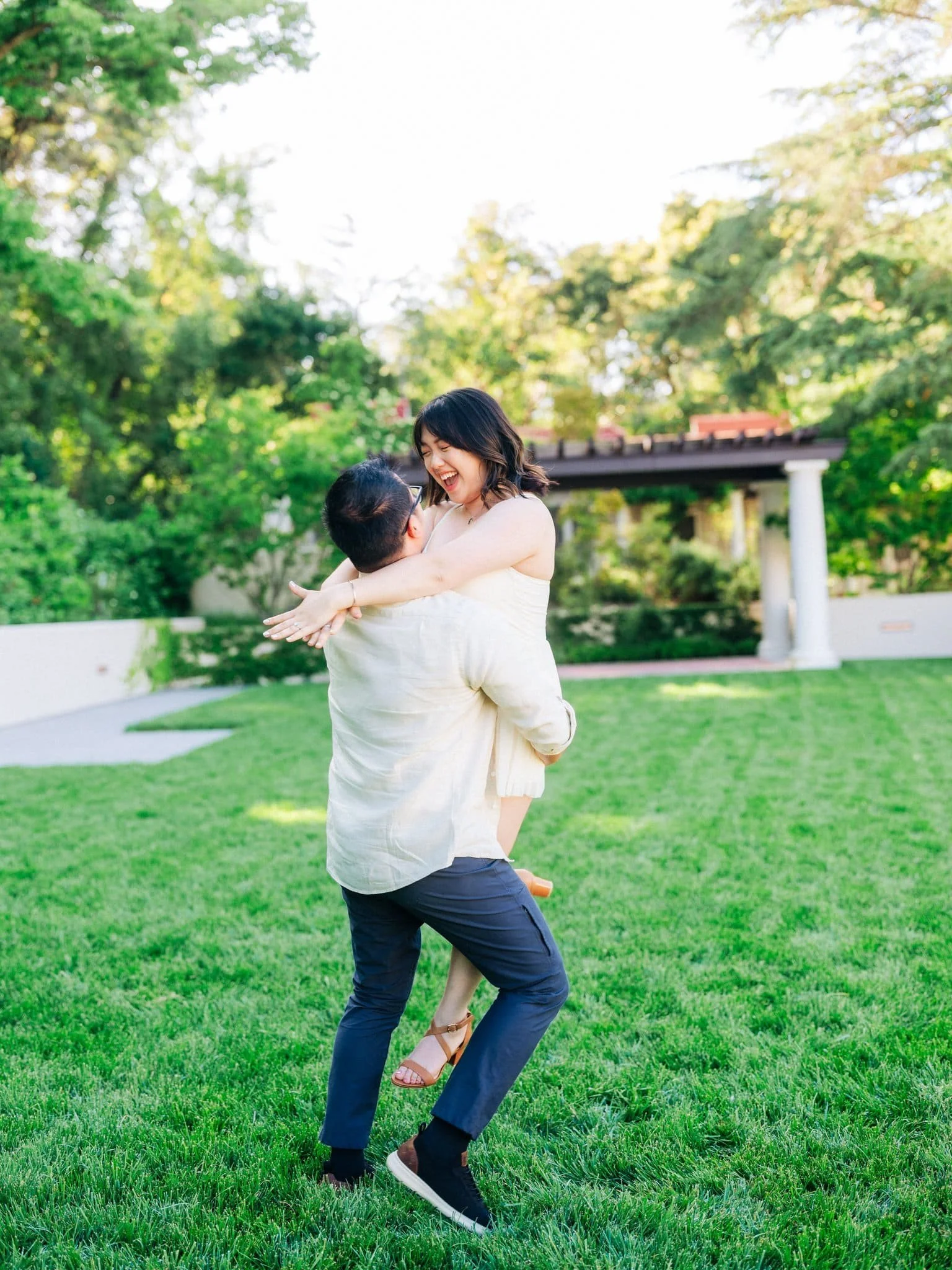 Bride-to-be jumping into his arms on the grass during their Montalvo Arts Center engagement photos in Saratoga.