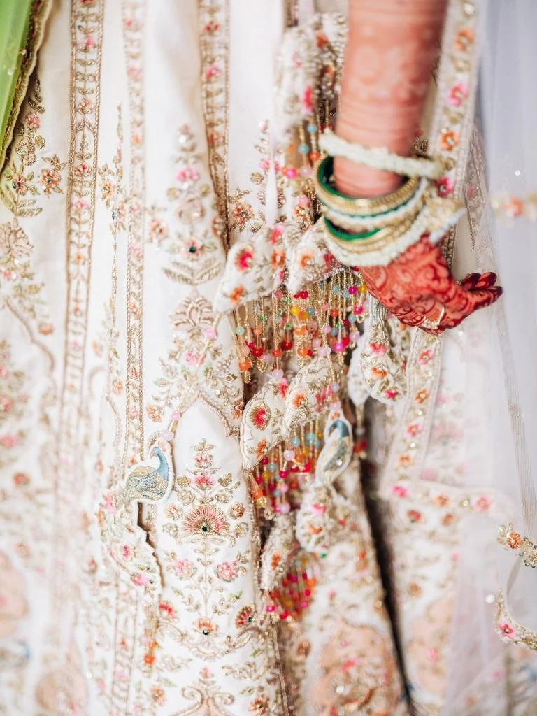 Close-up of the bride’s mehndi designs, bracelets, and floral wedding attire