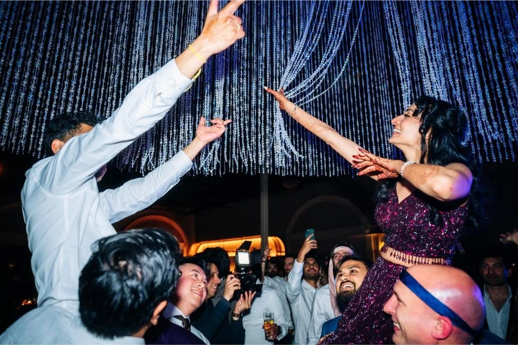 Bride and groom being lifted onto guests’ shoulders during the reception celebration