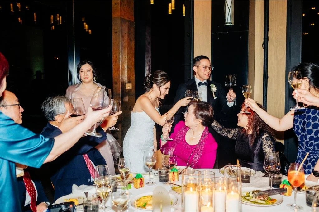 Bride smiling and talking with guests seated at a reception table