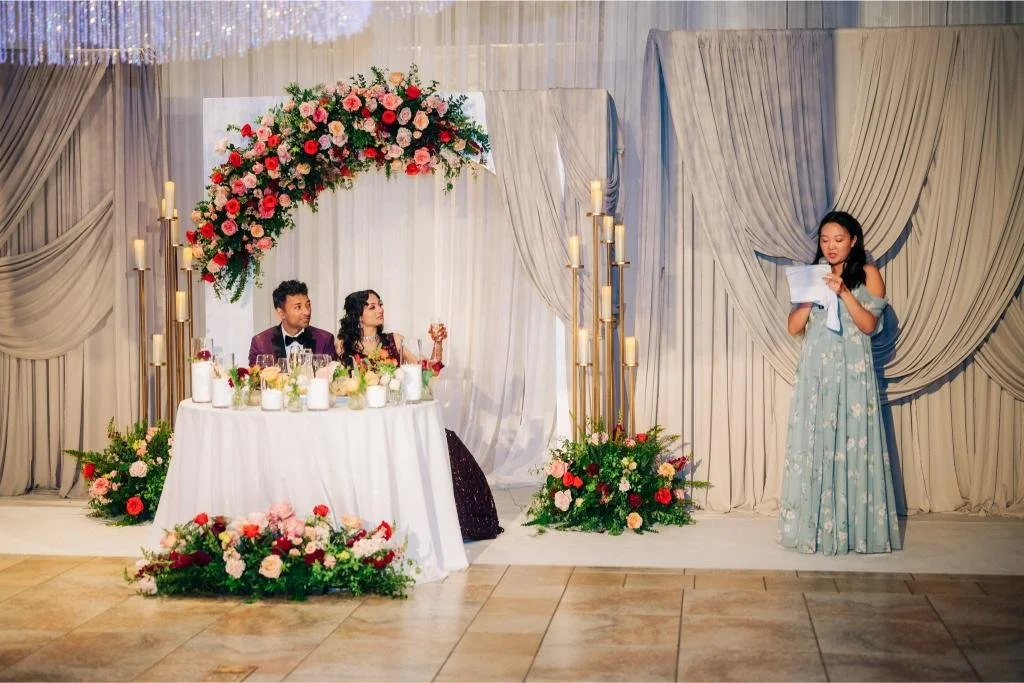 Bridesmaid giving a speech as the bride raises her glass during the reception