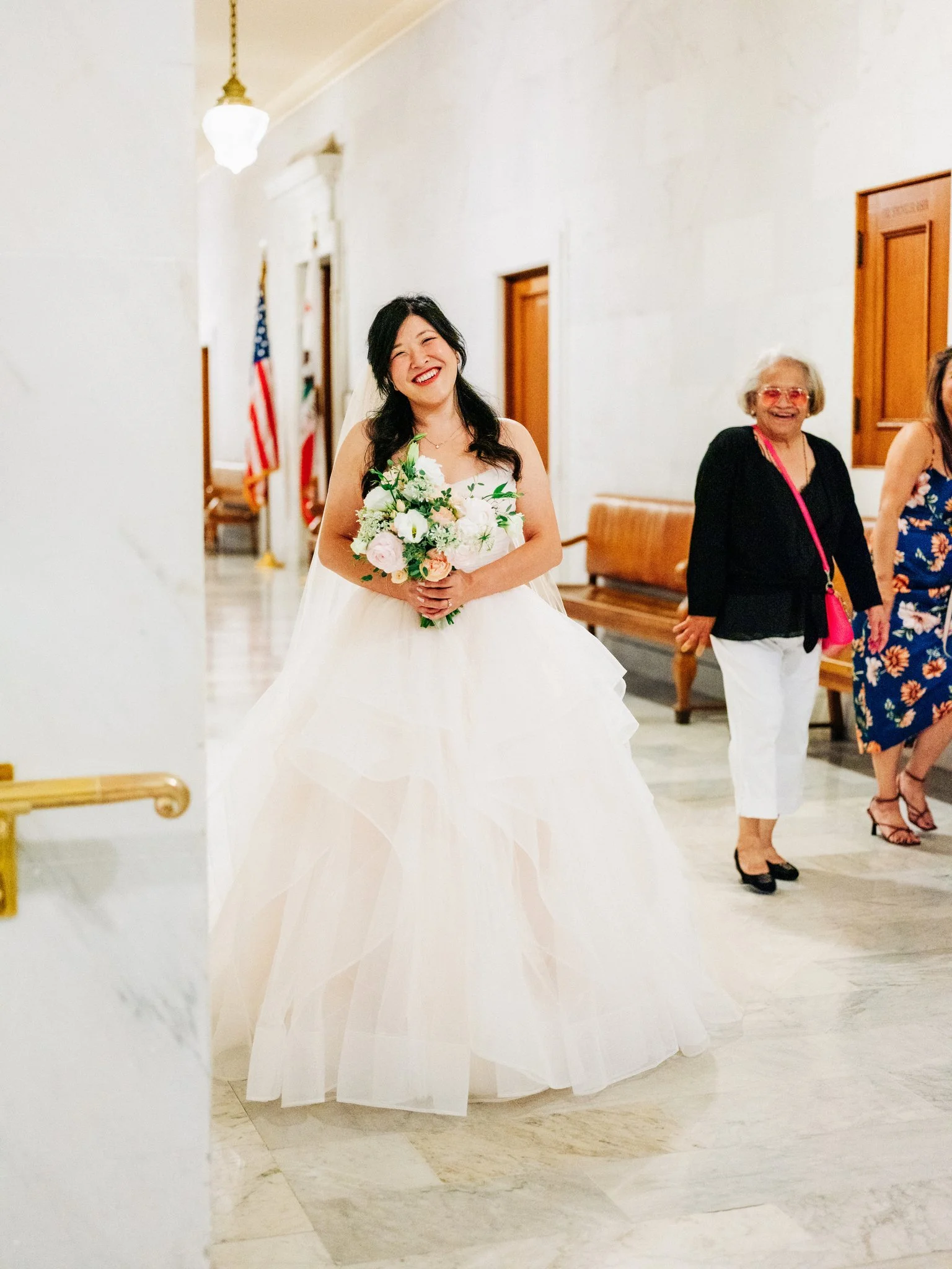 Bride posing with bouquet in elegant hallway at San Francisco City Hall wedding