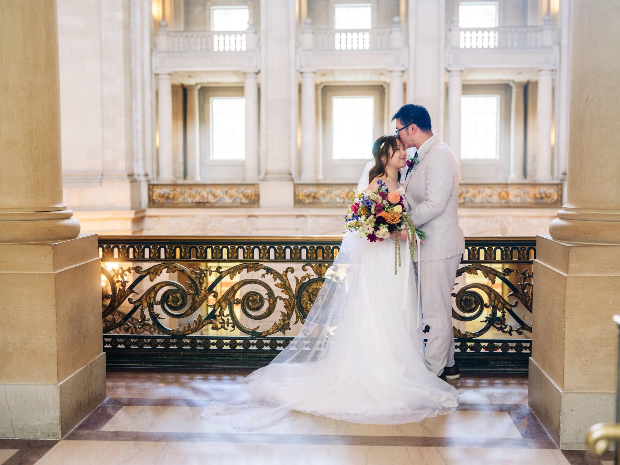 Bride and groom embracing on a balcony during their San Francisco City Hall elopement.