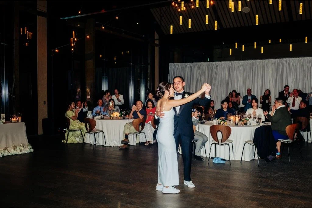 Bride and groom sharing their first dance as wedding guests watch