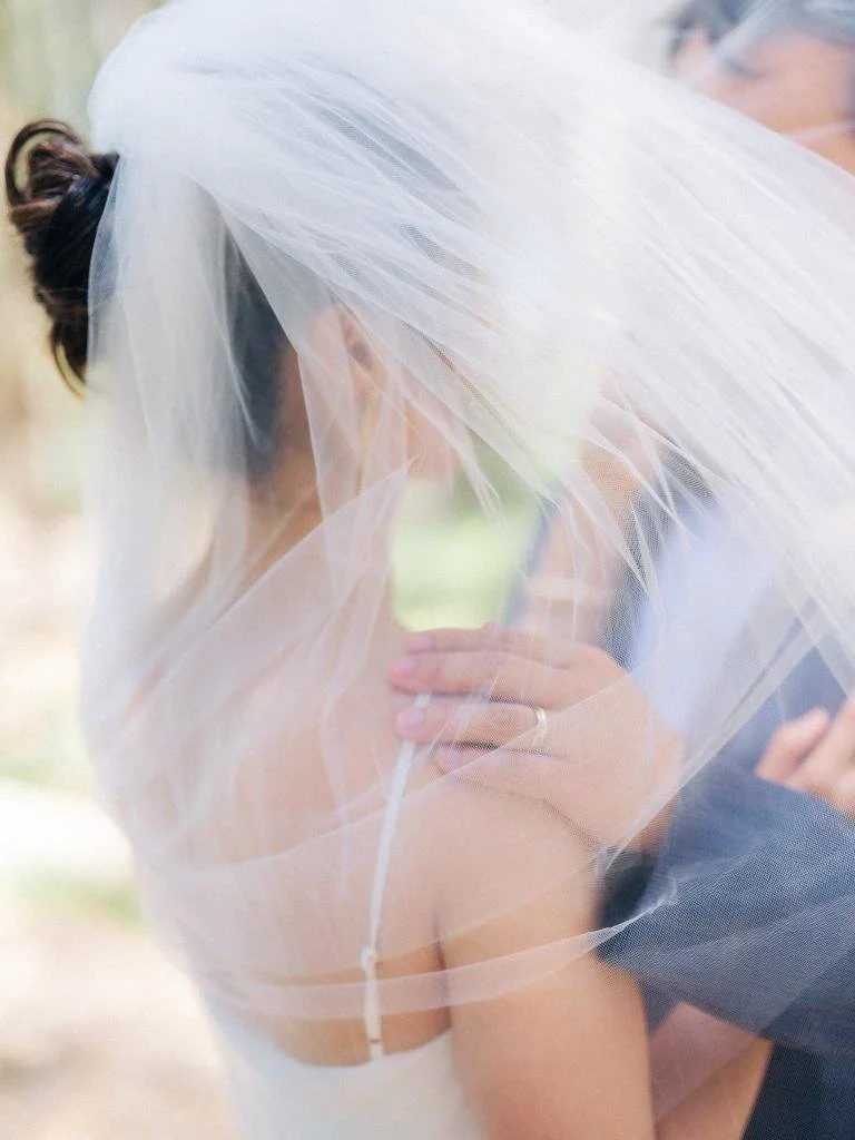 Bride and groom standing face to face as her veil blows over the groom's head at Lover's Lane.