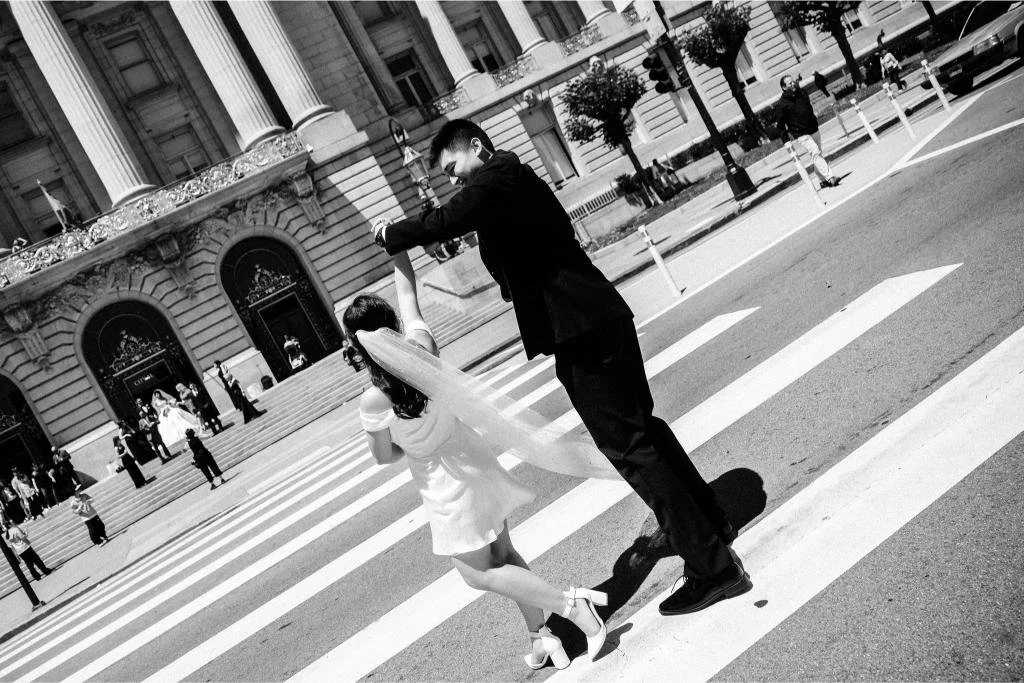 Groom twirling the bride in the crosswalk after their San Francisco City Hall wedding