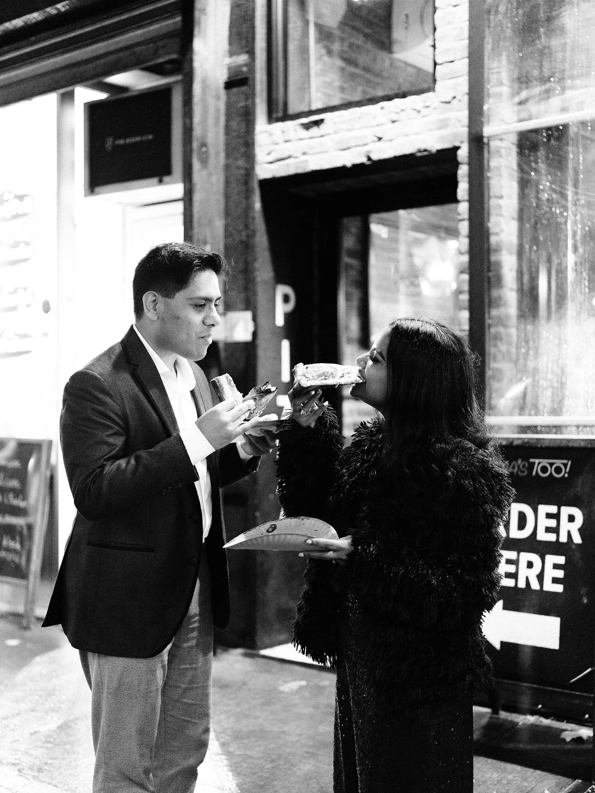 Couple eating pizza on New York City street during engagement session