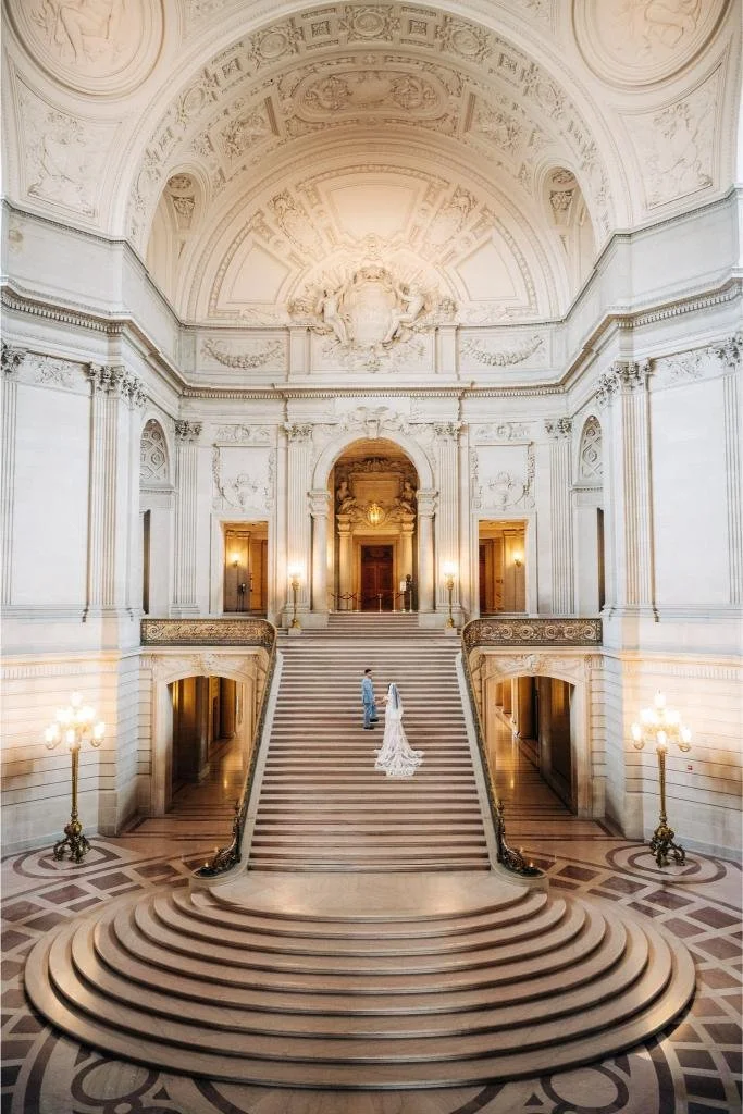 Bride and groom holding hands while climbing the Grand Staircase at San Francisco City Hall