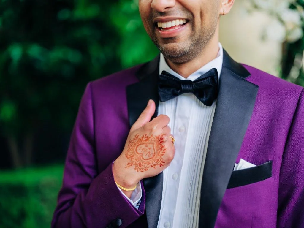 Close-up of the smiling groom with a mehndi design visible on his hand