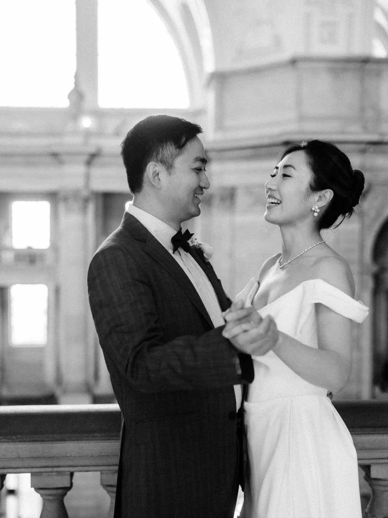 Bride and groom facing each other and holding hands as they slow dance inside San Francisco City Hall.