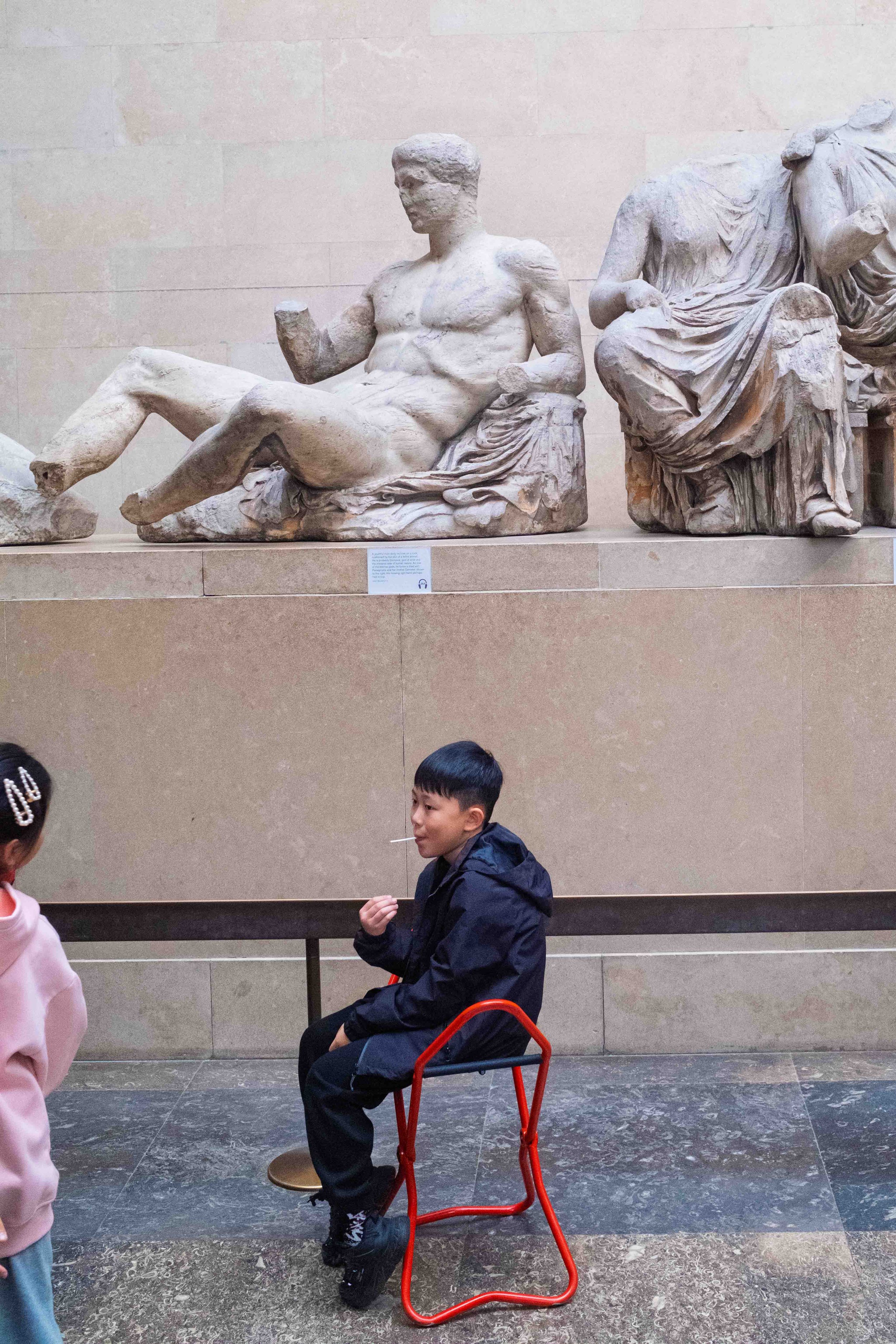 Children looking at ancient Greek sculptures in a museum.