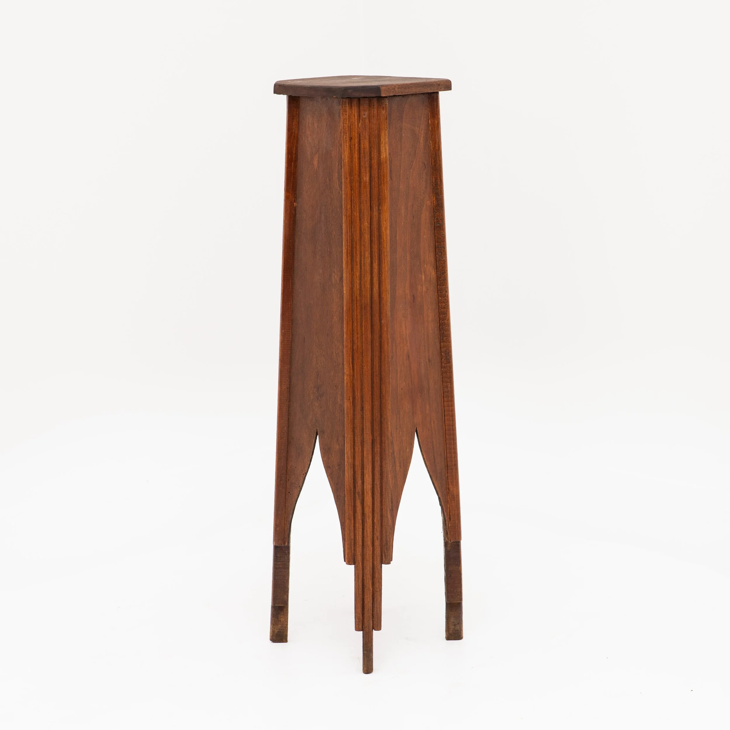 Sellette haute en bois, vers 1930. Structure fuselée à cannelures verticales, découpes en arc brisé et plateau carré.