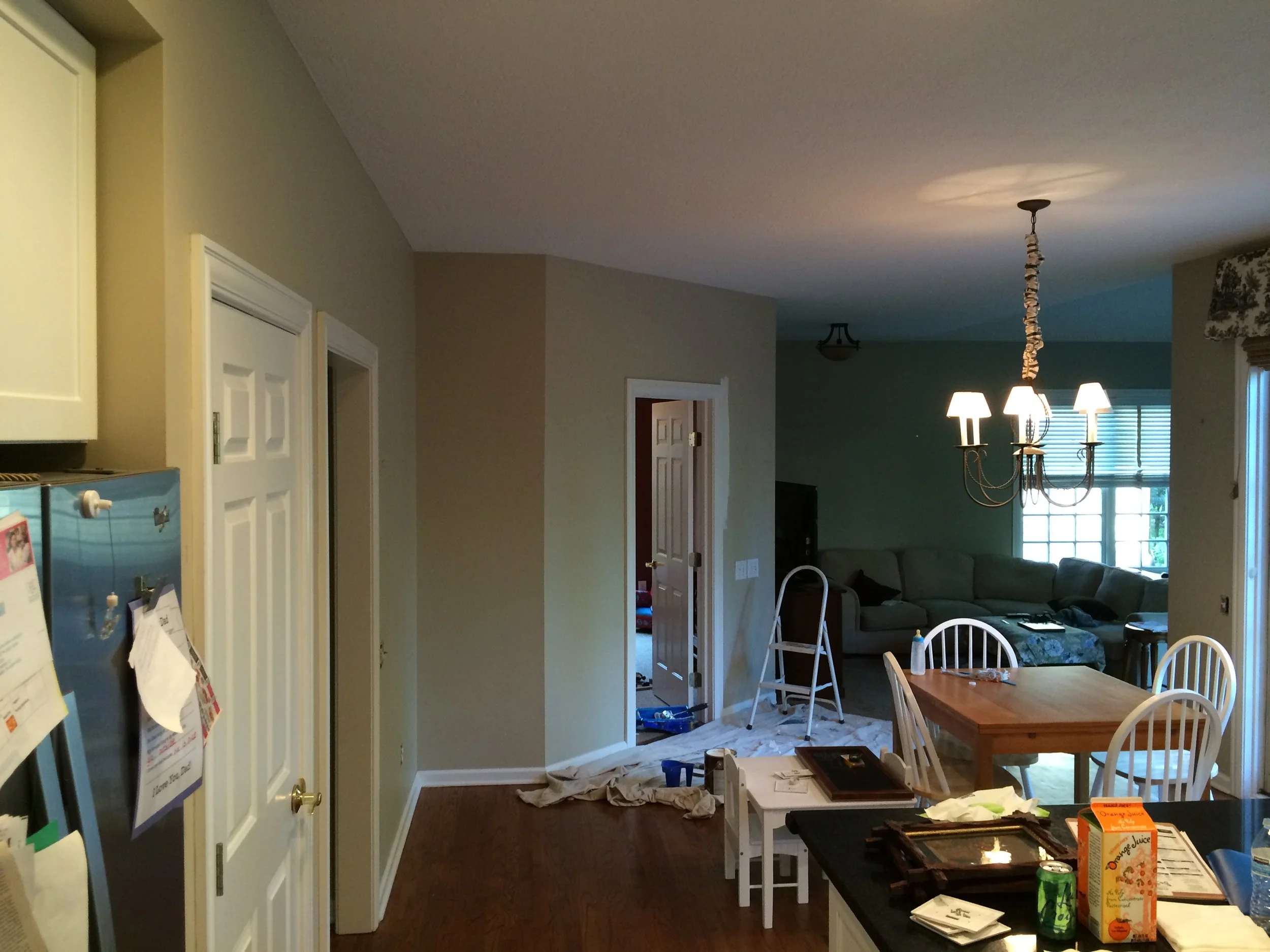 Interior view of a living and dining area with clutter, a chandelier hanging from the ceiling, and furniture.