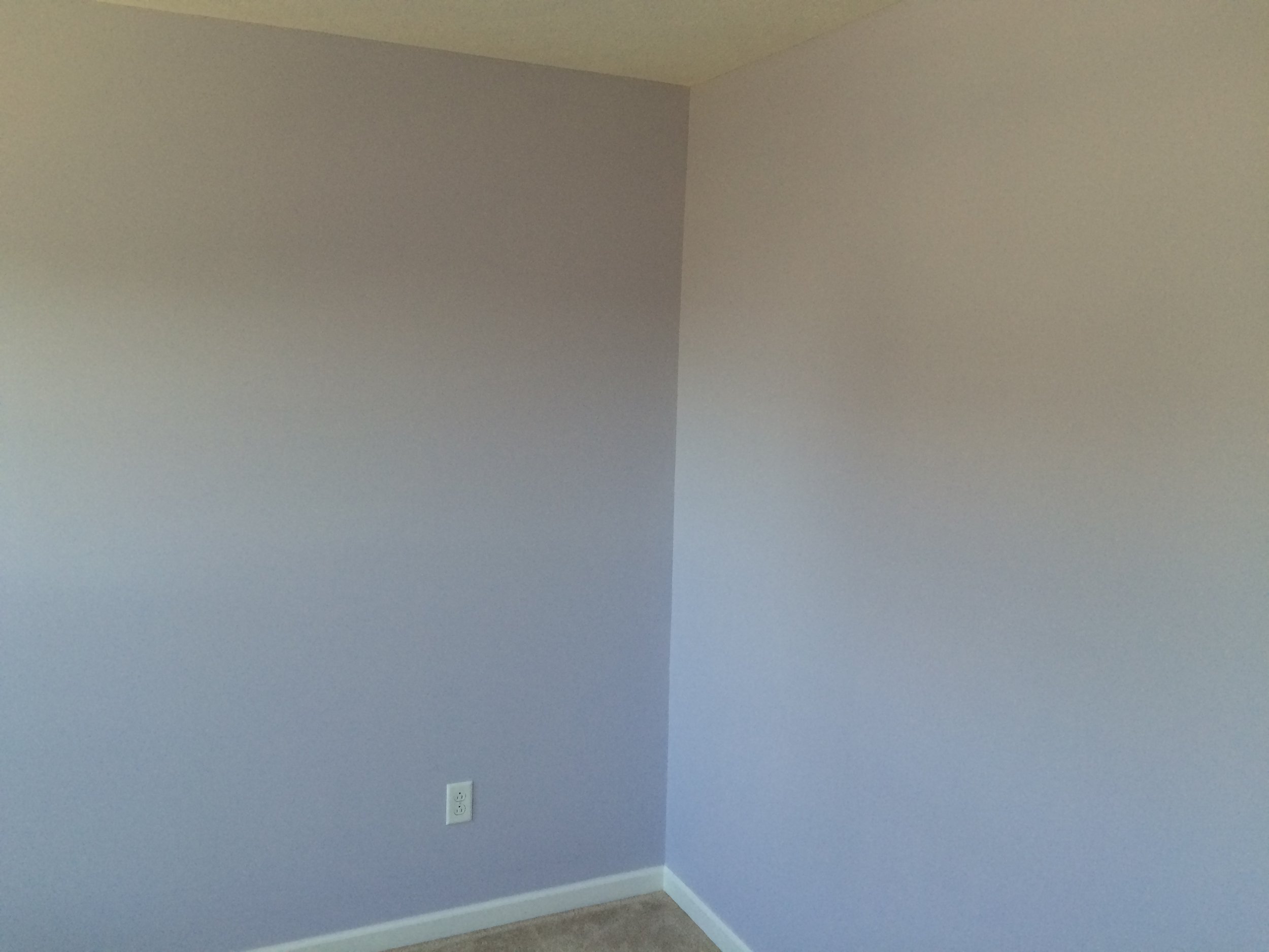 Empty room with light purple walls, electrical outlets, baseboards, and a ceiling.