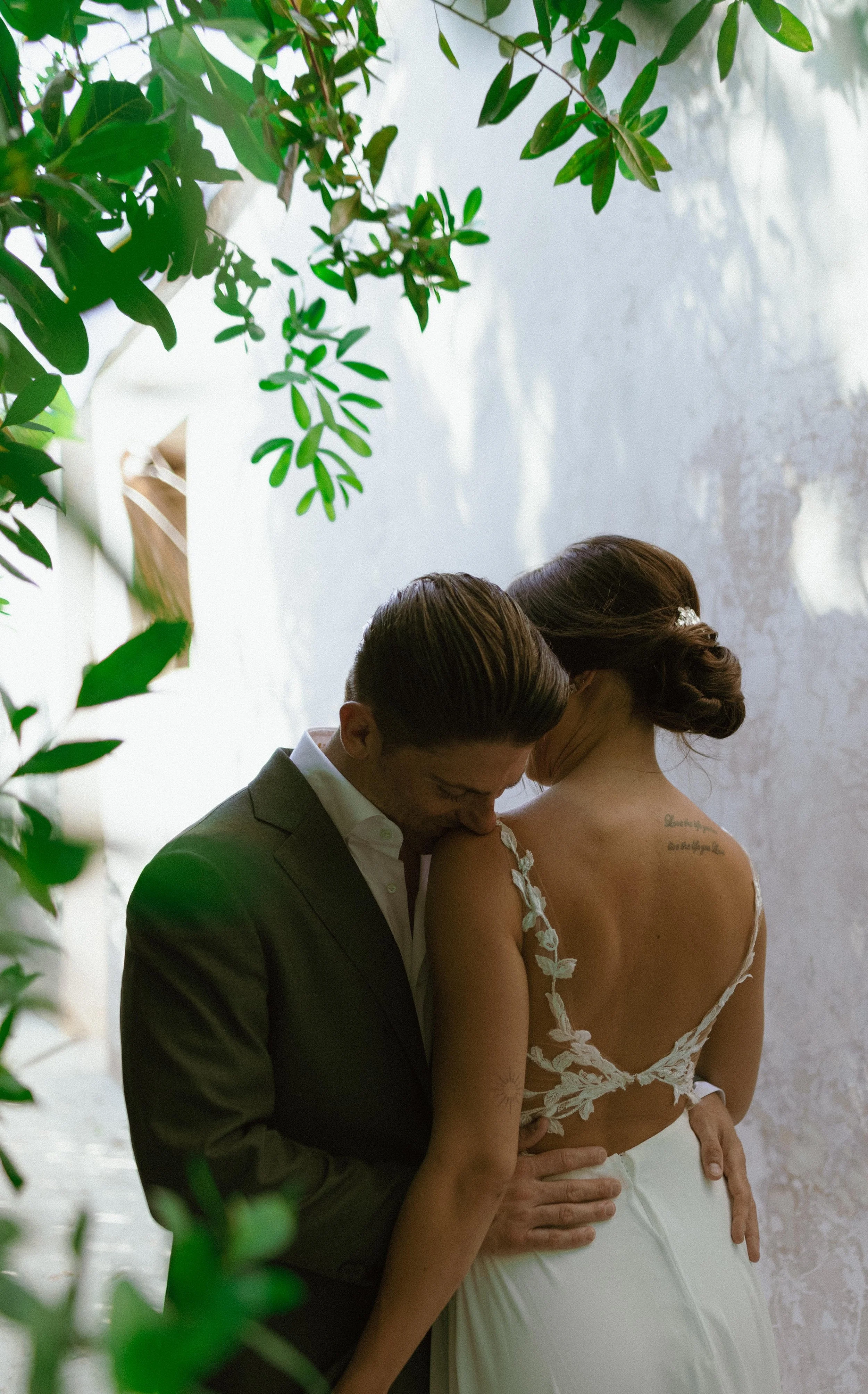 A groom and bride sharing an intimate moment at their wedding, surrounded by greenery.