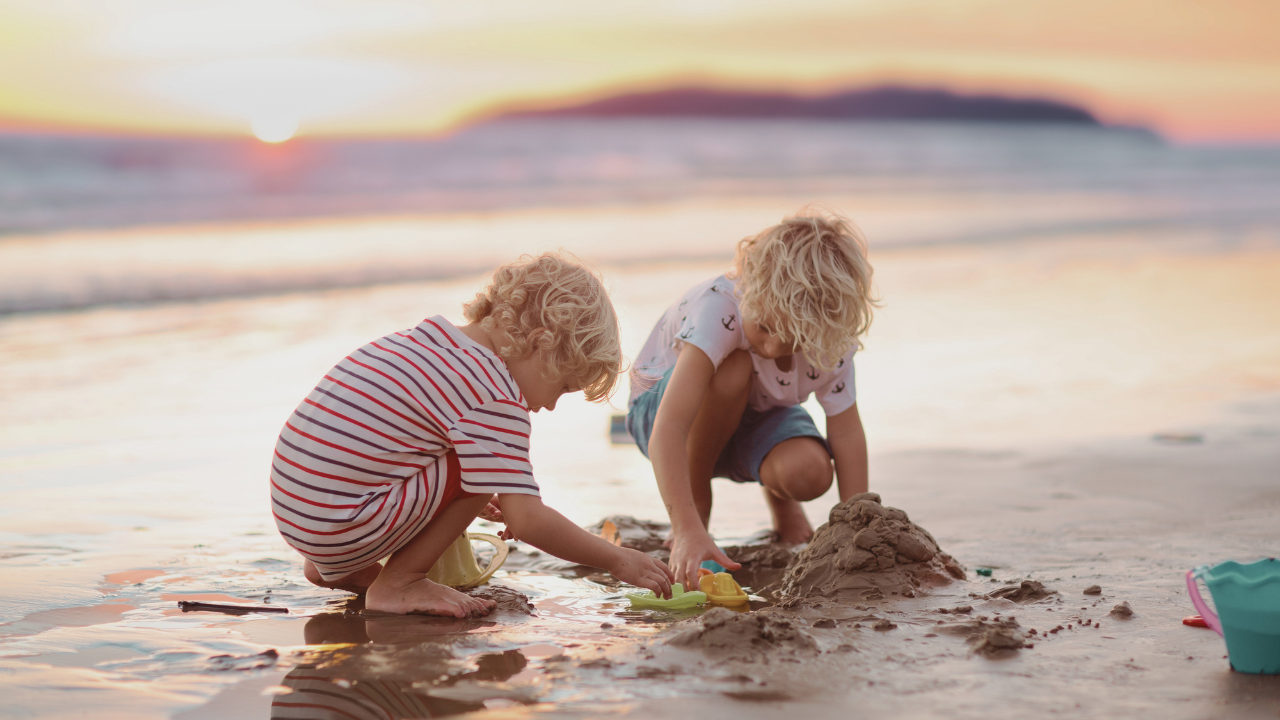 wo young children playing together in the sand at the beach.