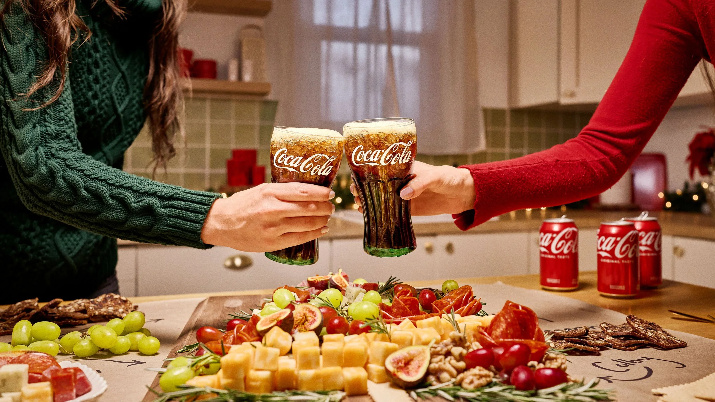 Two people toasting with Coca-Cola glasses over a holiday charcuterie spread for the Walmart campaign