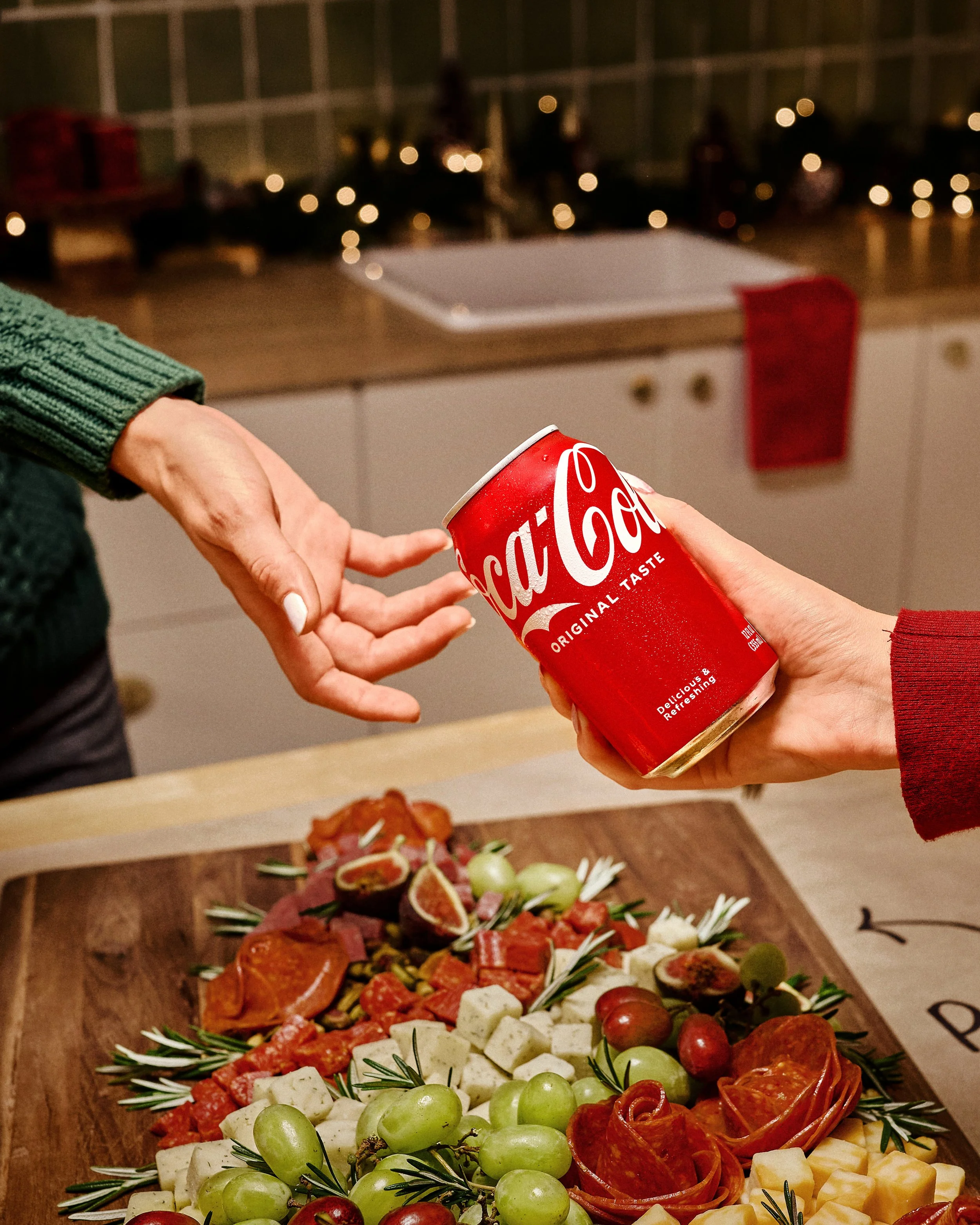 Hand holding a Coca-Cola Original Taste can in a styled kitchen scene for Walmart