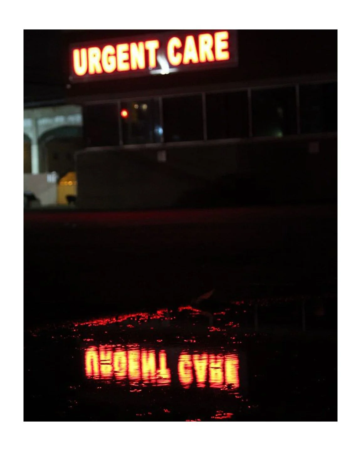 Bright red neon sign reading 'URGENT CARE' reflected in a wet surface at night.