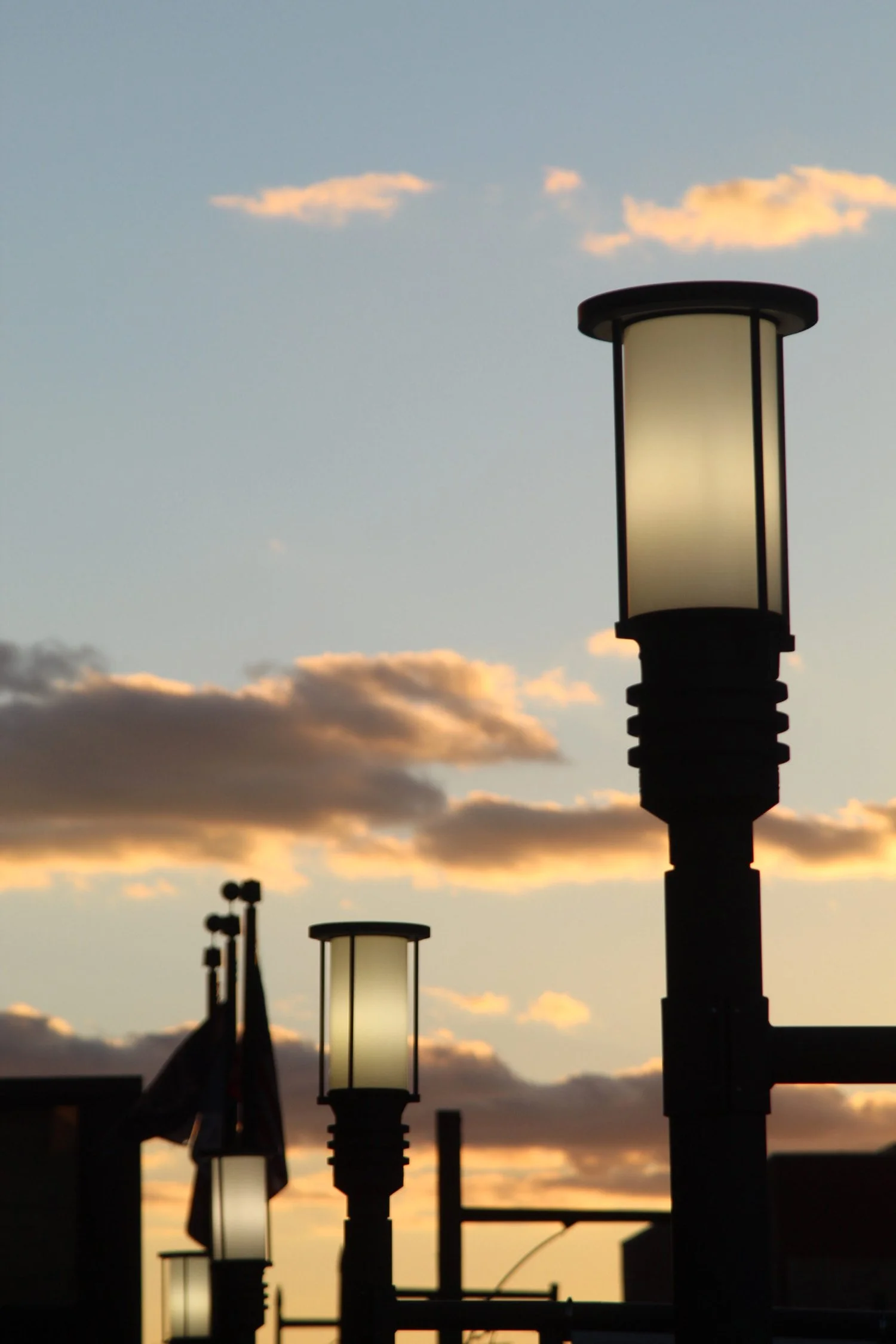 Street lamps against a sunset sky with clouds.
