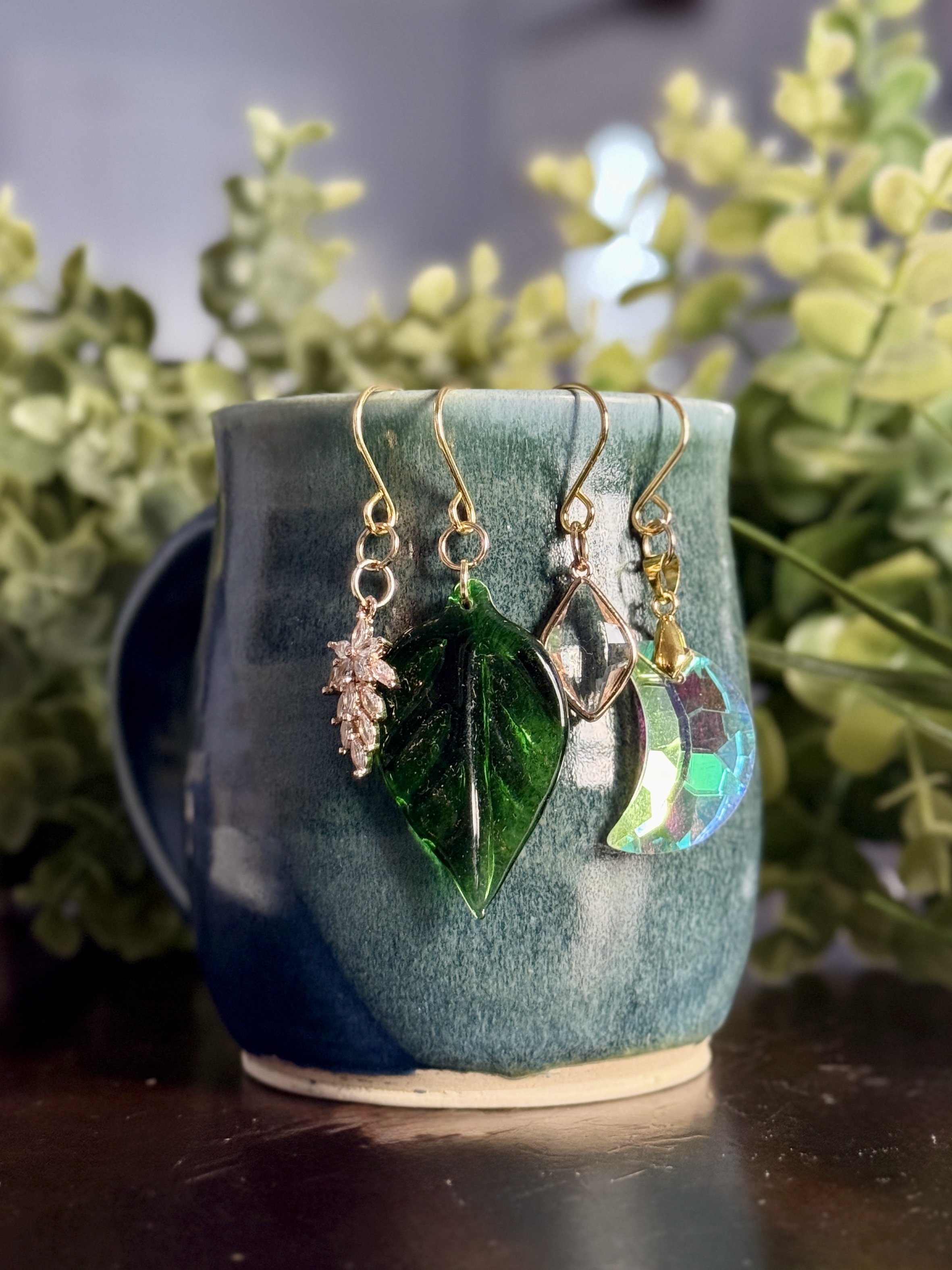 4th Front View of Crystal moon + antique glass leaf + 2 crystal pendant plant charms of a mug with leafy background