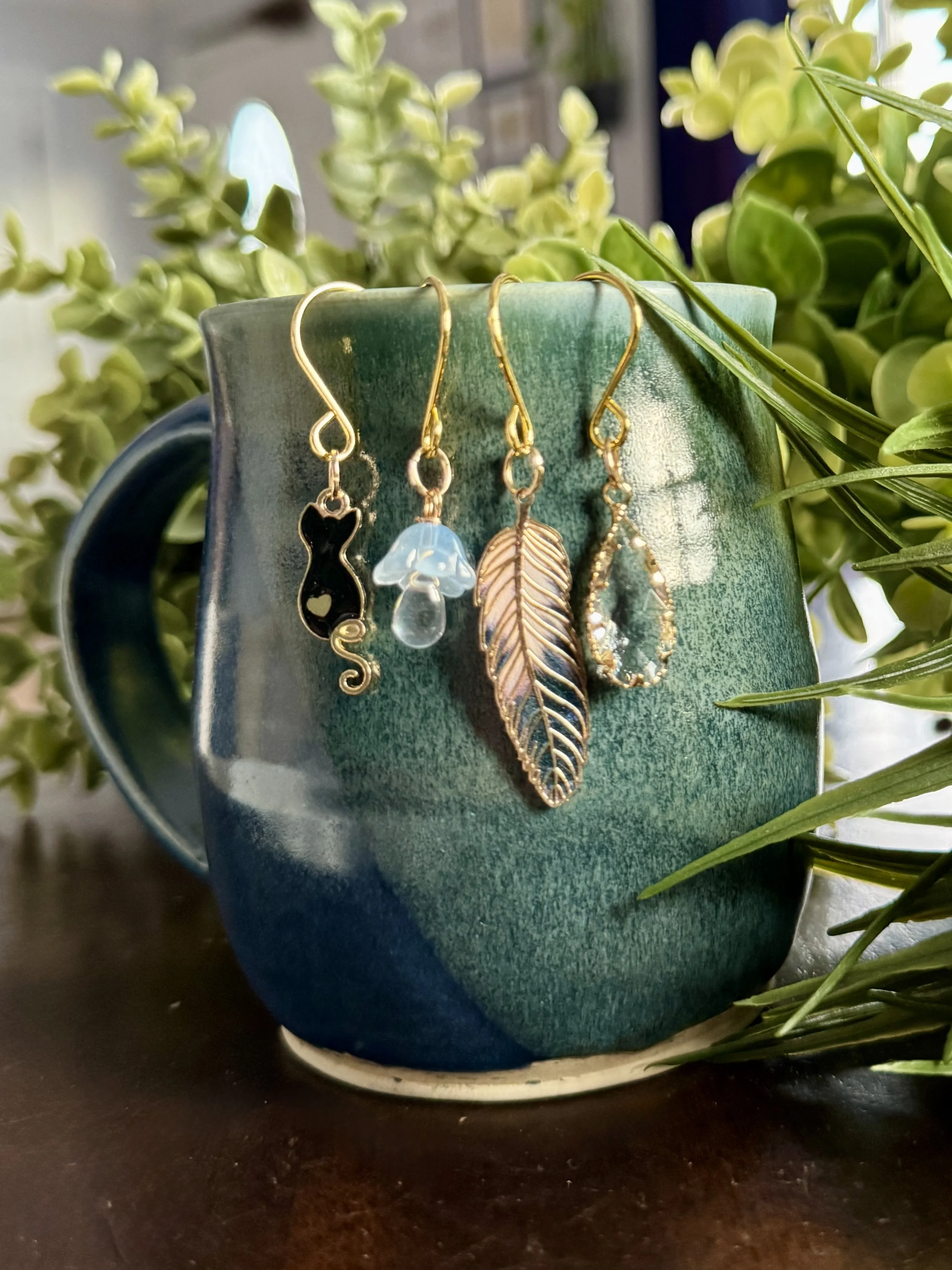 Alternative zoom out front view of Black cat + feather + mushroom + crystal plant charms on a leafy background