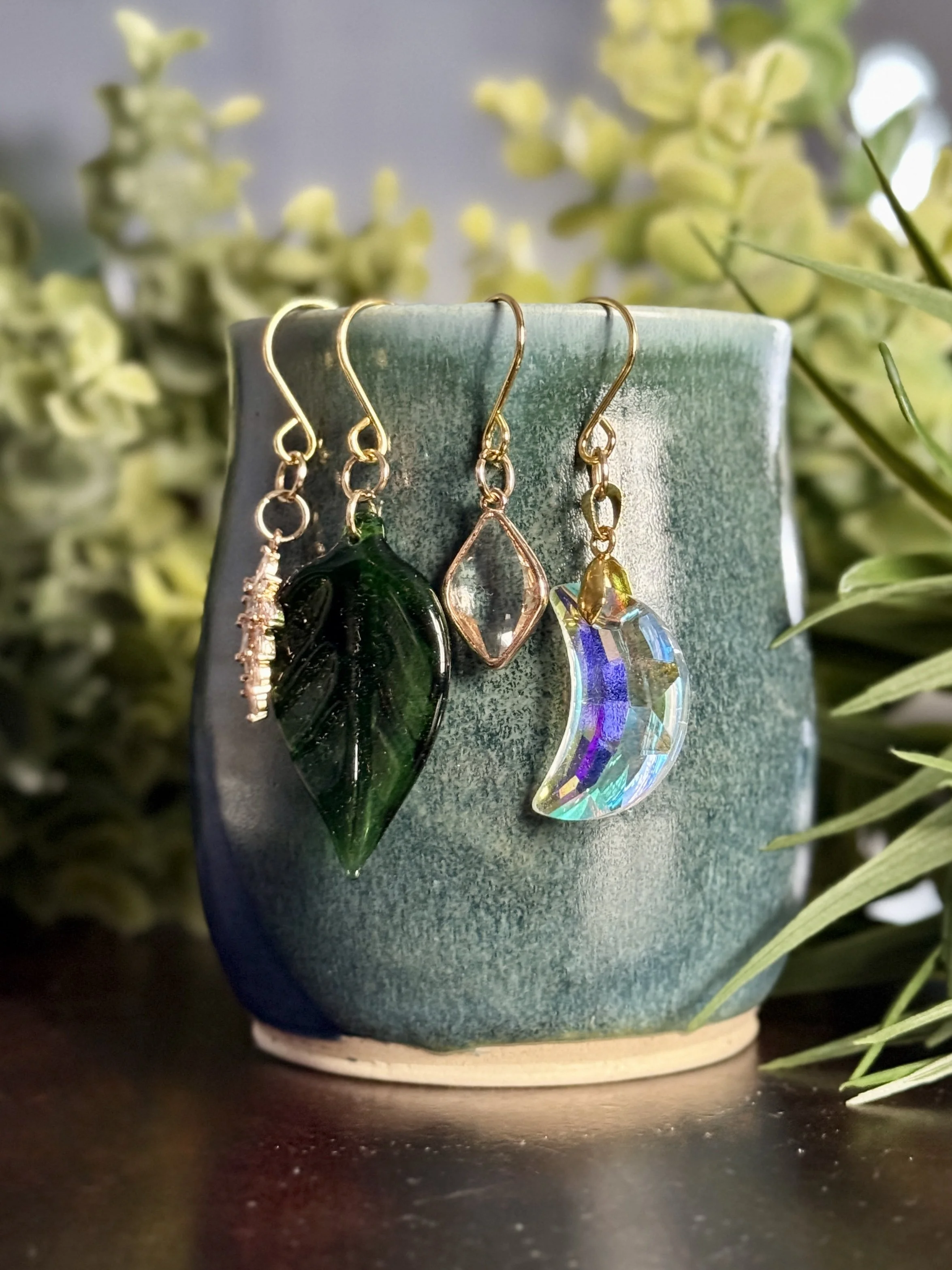 7th Front View of Crystal moon + antique glass leaf + 2 crystal pendant plant charms of a mug with leafy background