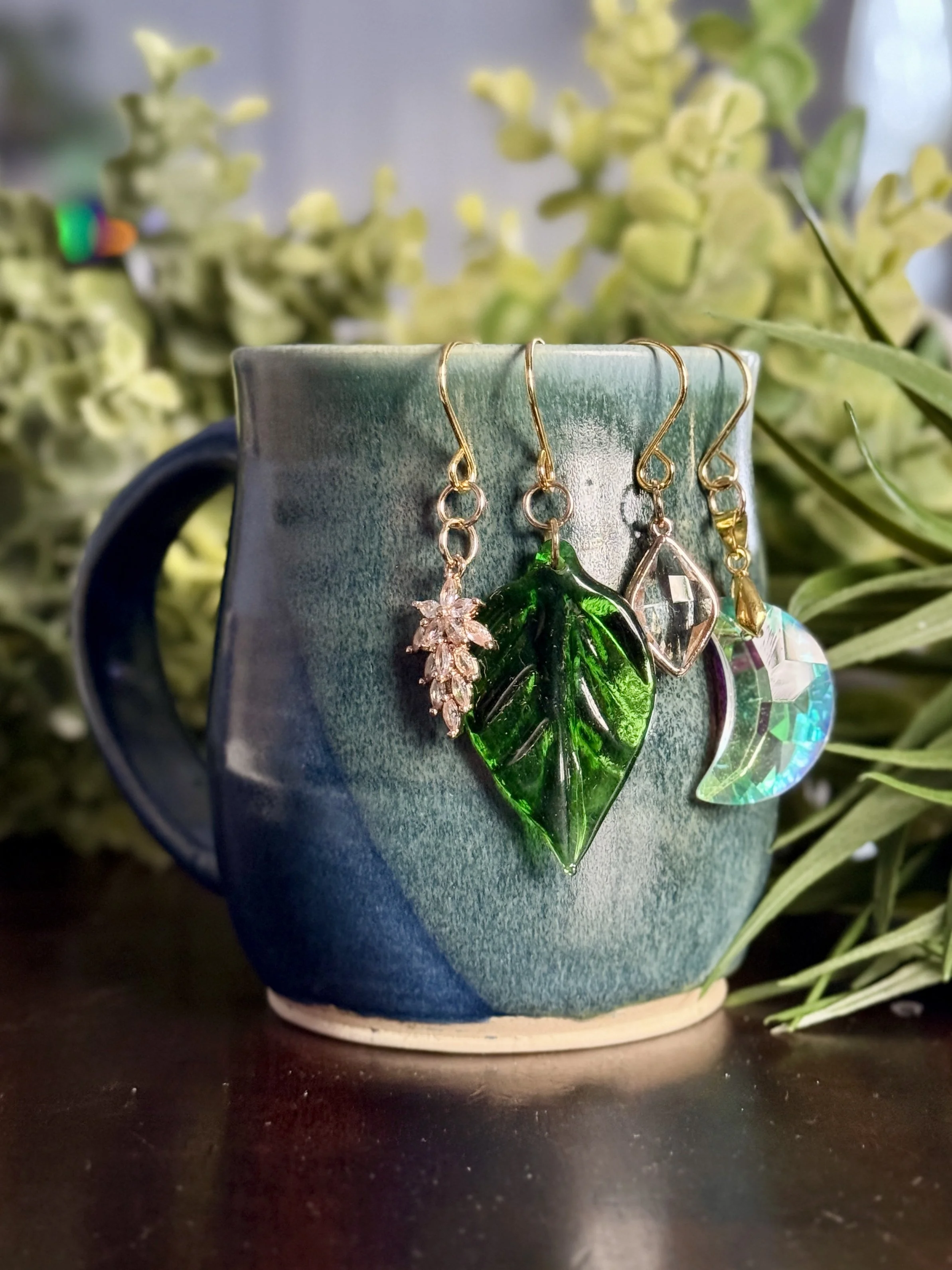 8th Front View of Crystal moon + antique glass leaf + 2 crystal pendant plant charms of a mug with leafy background