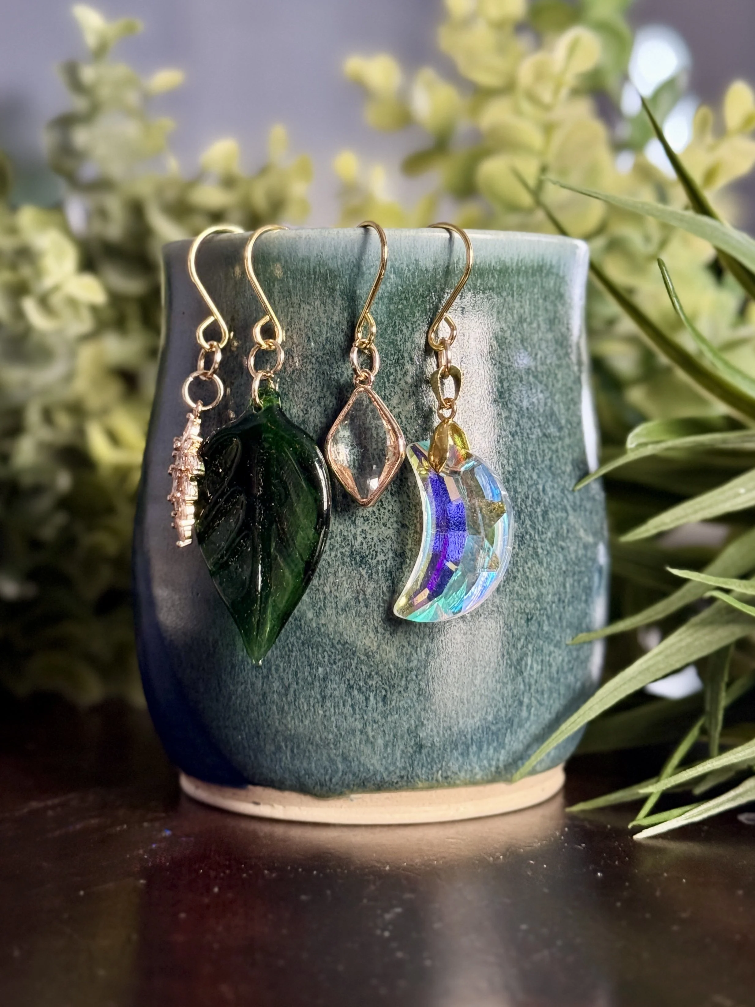 6th Front View of Crystal moon + antique glass leaf + 2 crystal pendant plant charms of a mug with leafy background