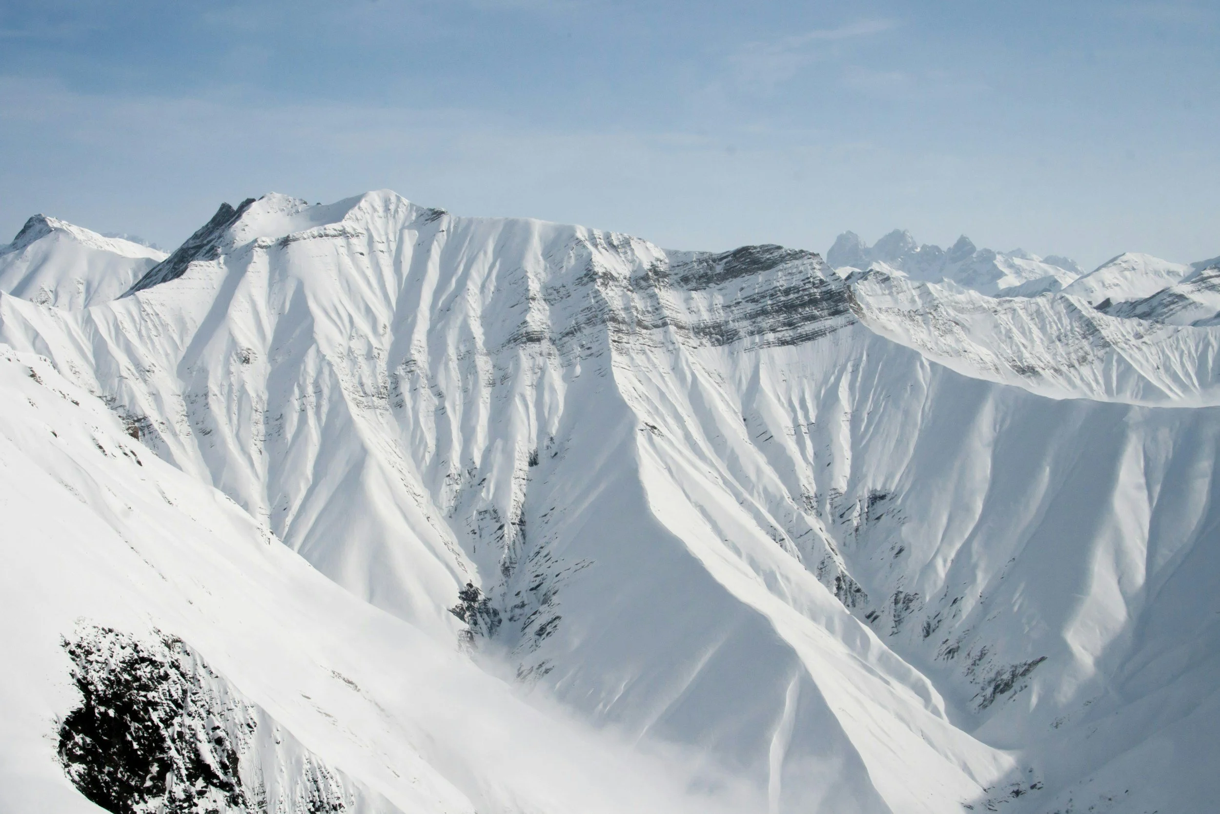 Snow-covered mountain range under a partly cloudy sky.