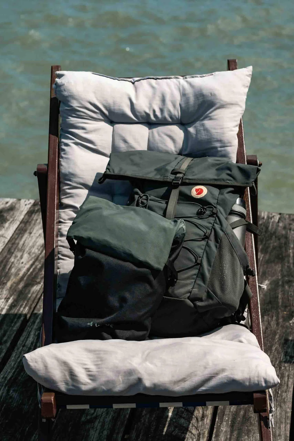 Two different daypacks laying on a lounger at the edge of the water. 