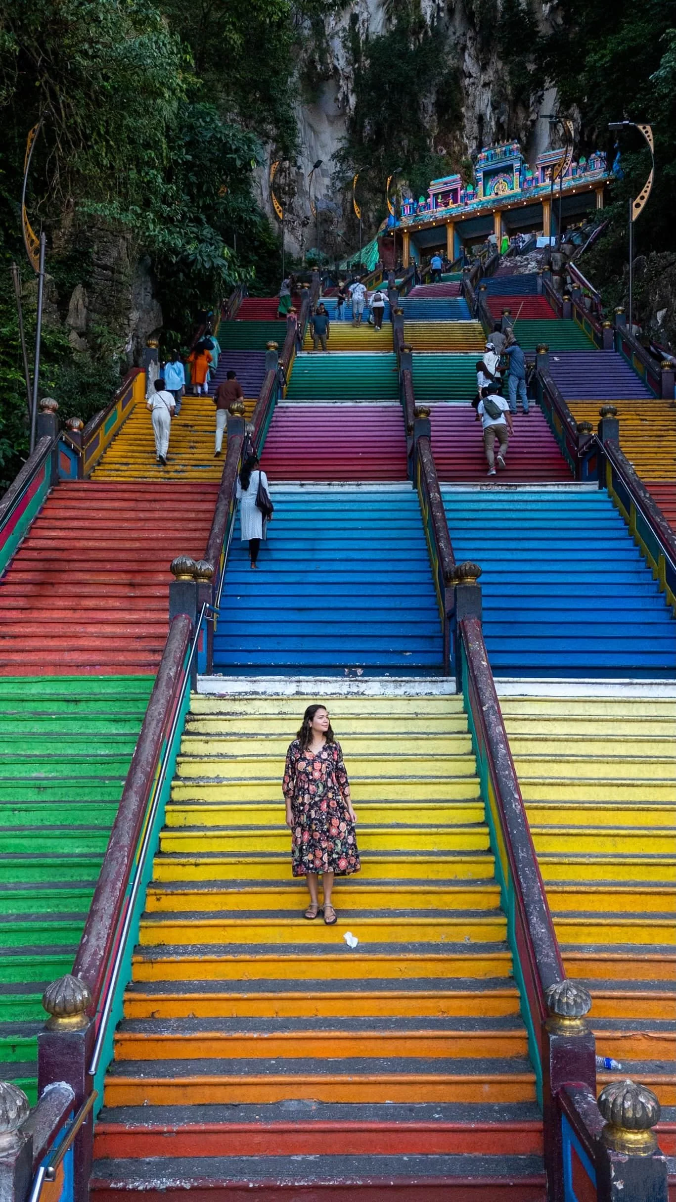 A traveler posing on rainbow stairs at Batu Caves